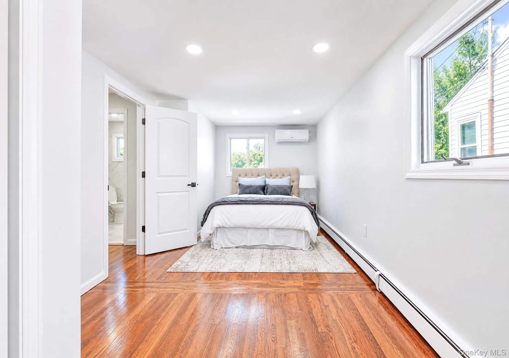 Bedroom featuring wood-finish flooring, recessed lighting, and a split-unit air conditioning system Bedroom featuring wood-finish flooring, recessed lighting, and a split-unit air conditioning system