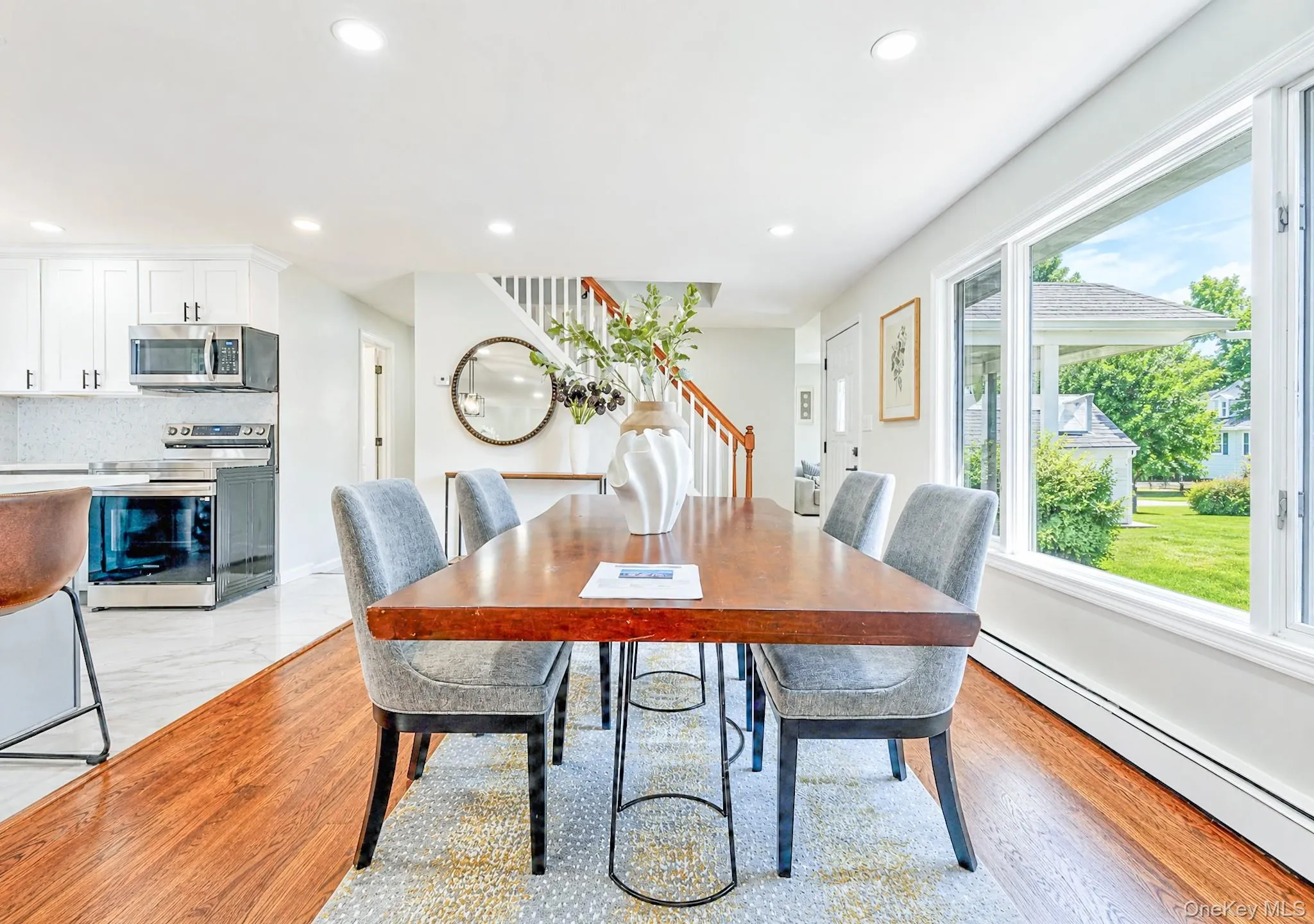 Spacious dining area featuring rich wood-finish flooring, abundant natural light from large windows, recessed lighting, and an open concept layout Spacious dining area featuring rich wood-finish flooring, abundant natural light from large windows, recessed lighting, and an open concept layout