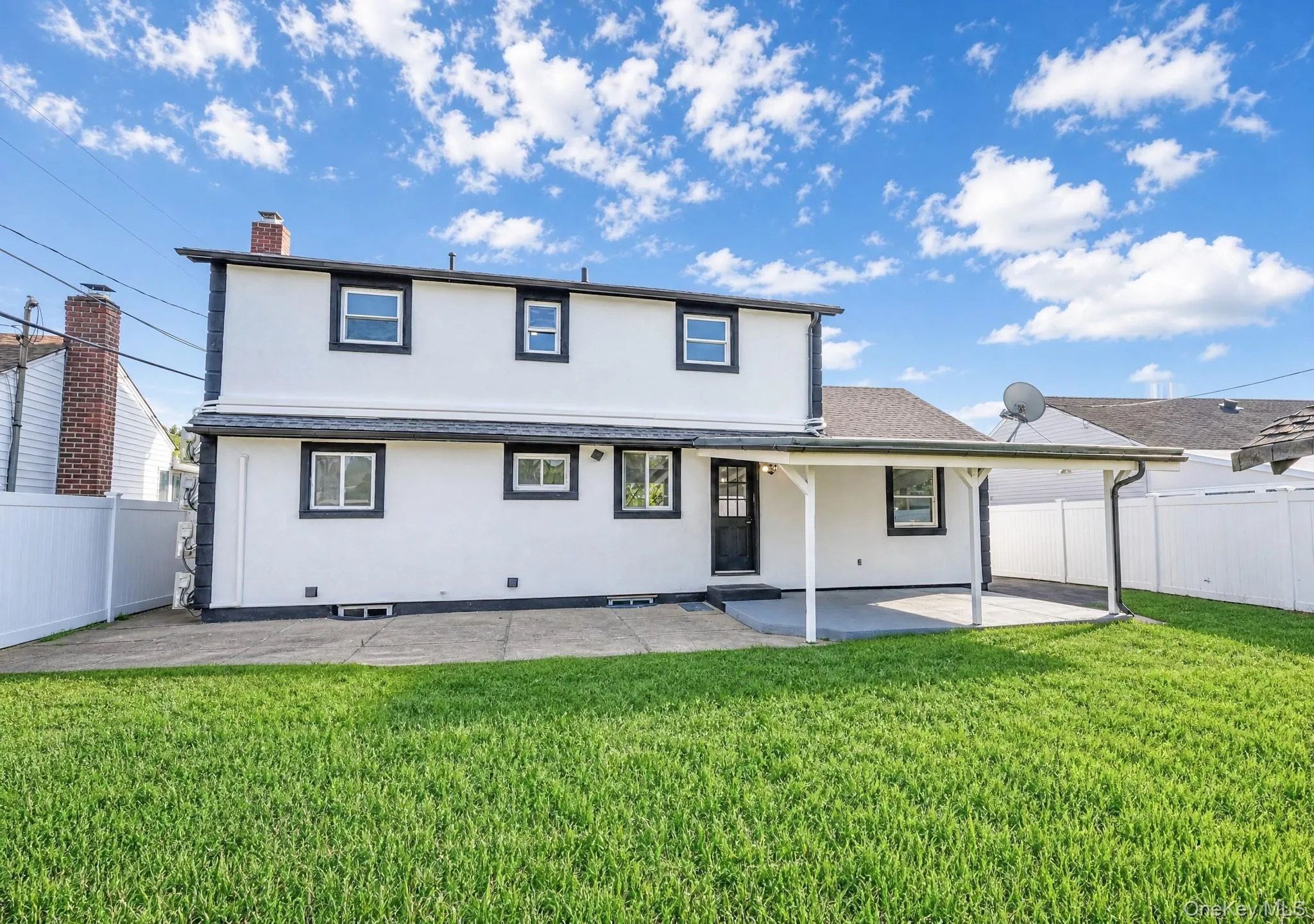Expansive rear yard featuring a covered patio, manicured lawn, and privacy fencing Expansive rear yard featuring a covered patio, manicured lawn, and privacy fencing