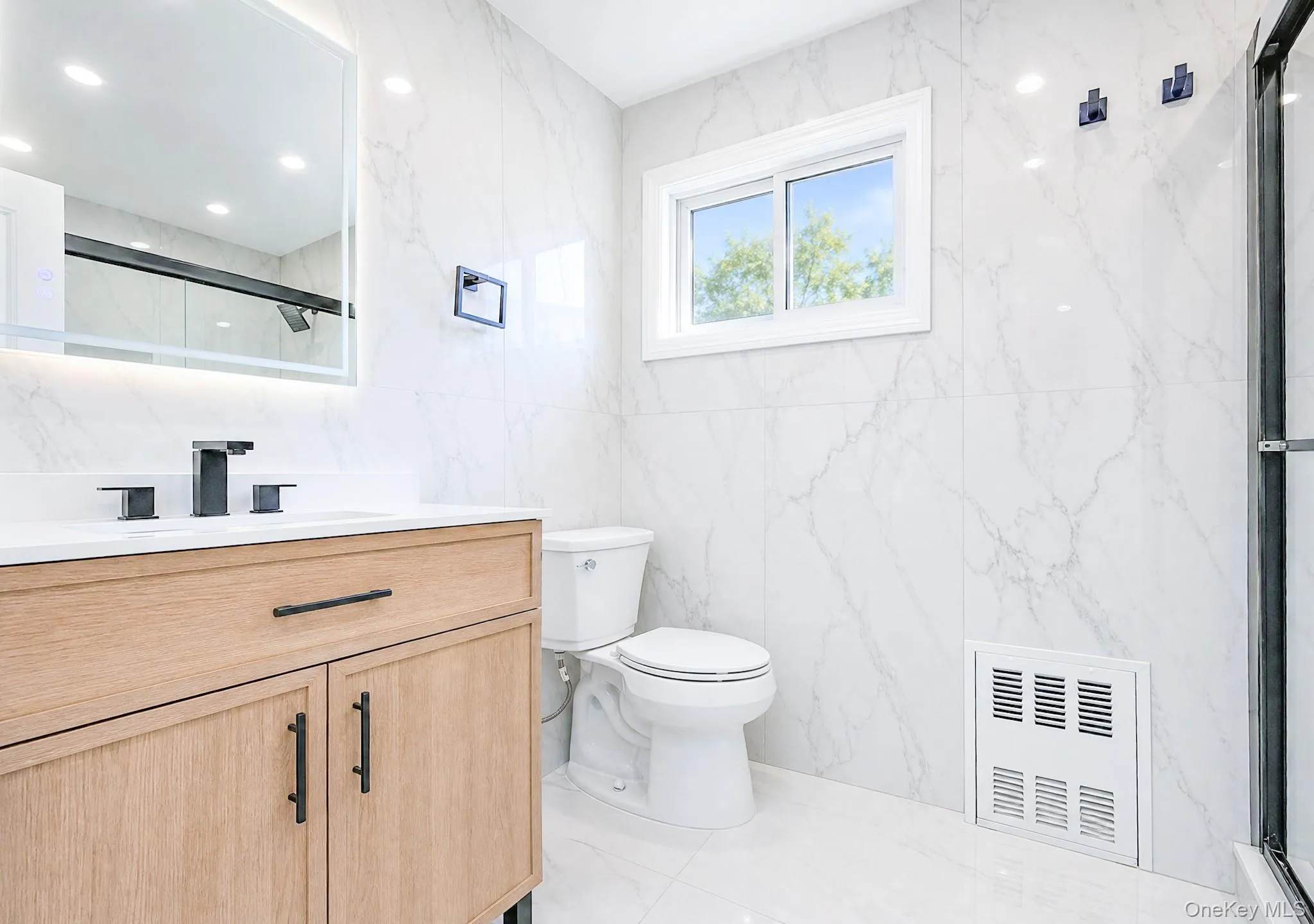 Modern bathroom featuring a wood-finish vanity with a white countertop and matte black fixtures Modern bathroom featuring a wood-finish vanity with a white countertop and matte black fixtures