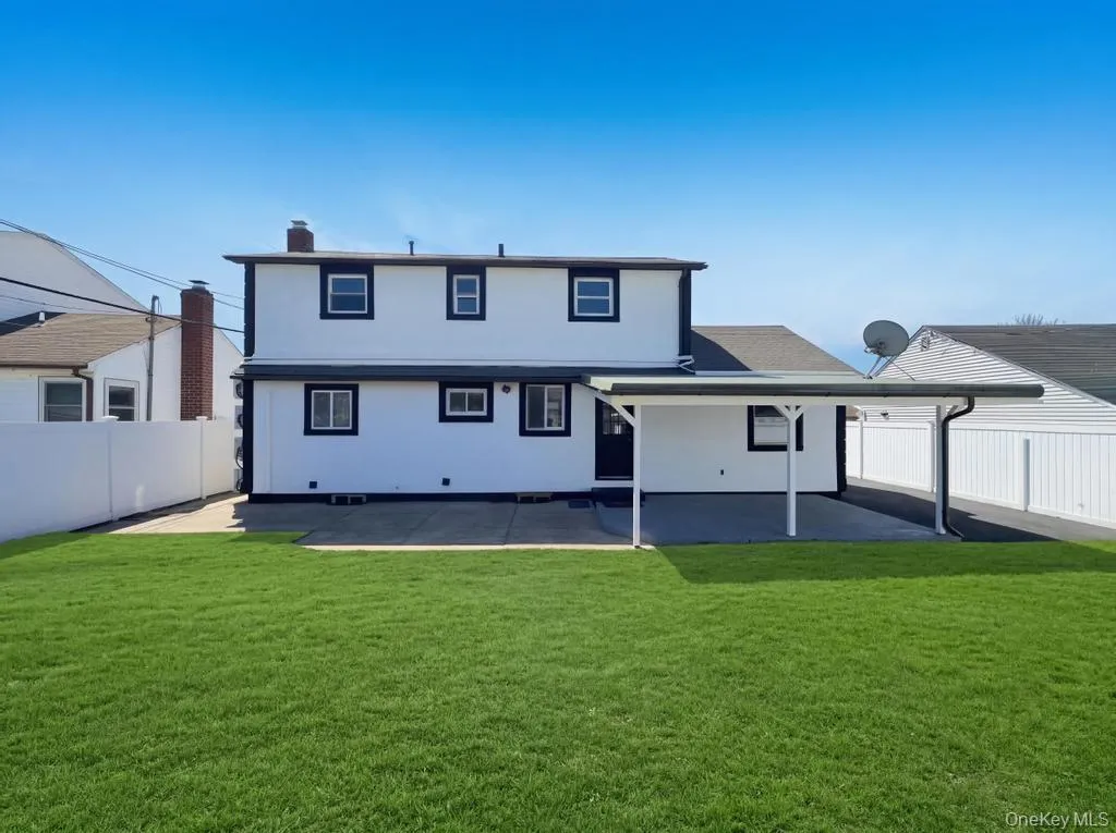 Expansive green lawn with a white two-story exterior featuring dark trim, a covered patio, and a privacy fence Expansive green lawn with a white two-story exterior featuring dark trim, a covered patio, and a privacy fence