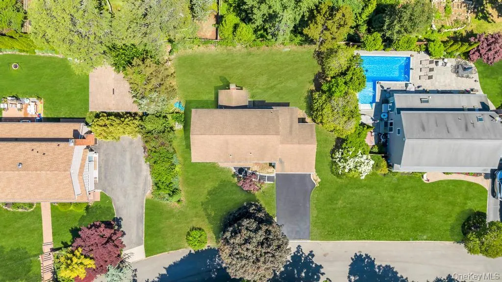 Expansive property featuring a central residence with a brown shingle roof, a paved driveway, and surrounding green lawns Expansive property featuring a central residence with a brown shingle roof, a paved driveway, and surrounding green lawns