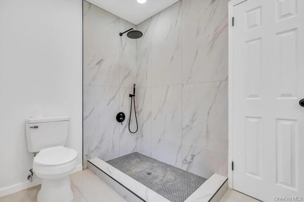 Walk-in shower with large-format marble-look wall tiling and a mosaic tile floor Walk-in shower with large-format marble-look wall tiling and a mosaic tile floor