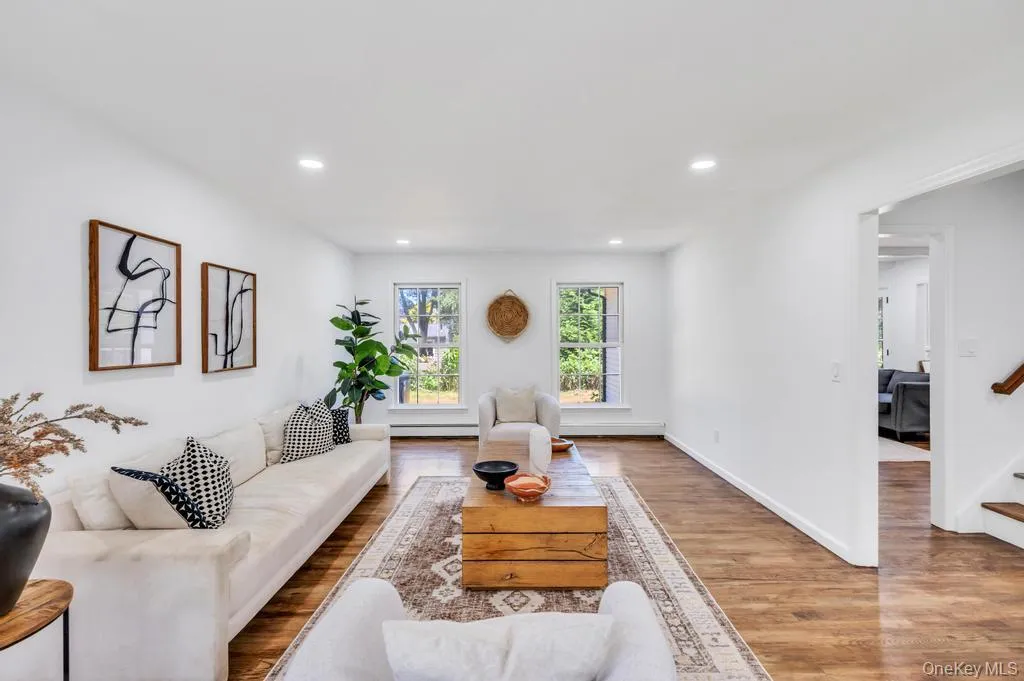 Spacious living area featuring wood-finish flooring, recessed lighting, and white walls Spacious living area featuring wood-finish flooring, recessed lighting, and white walls