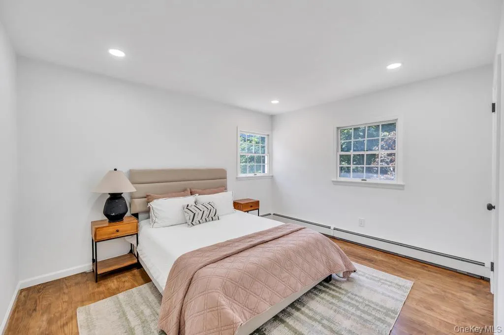 Spacious room featuring wood-finish flooring, recessed lighting, and two multi-pane windows Spacious room featuring wood-finish flooring, recessed lighting, and two multi-pane windows