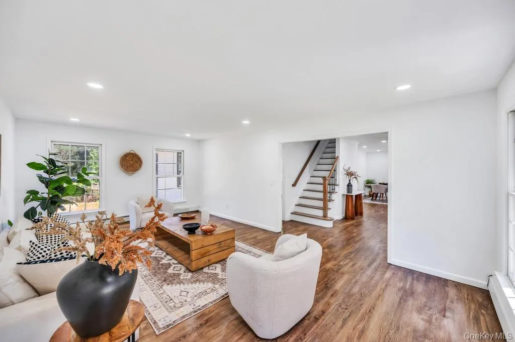 Spacious living area featuring wood-finish flooring, recessed lighting, and white trim Spacious living area featuring wood-finish flooring, recessed lighting, and white trim