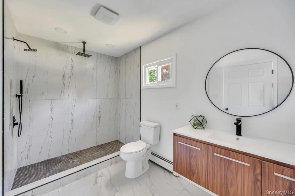 Spacious bathroom featuring a walk-in shower with dual showerheads and marble-look wall tiling Spacious bathroom featuring a walk-in shower with dual showerheads and marble-look wall tiling