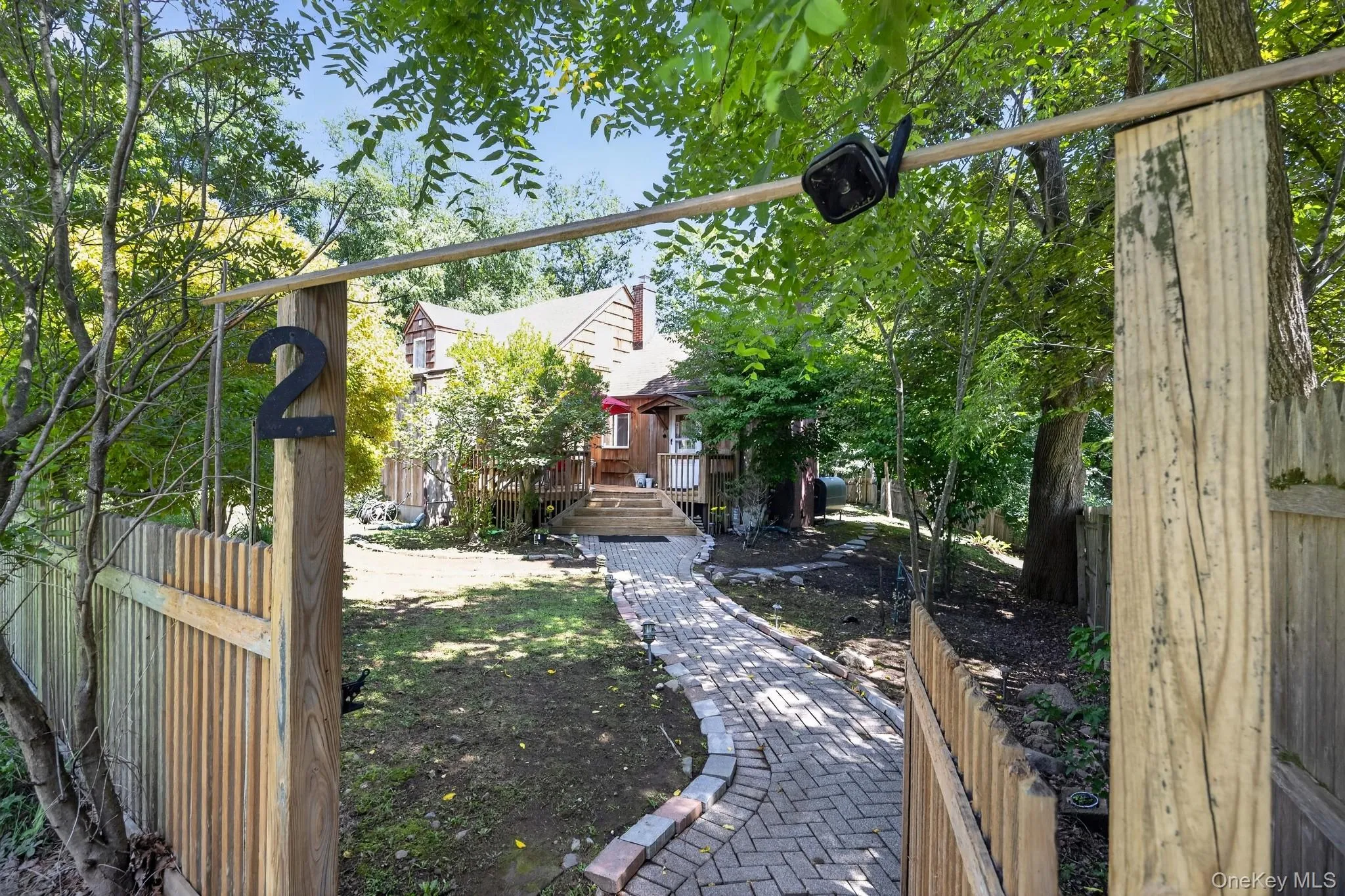 Brick paver walkway leading to a wood-sided residence with an elevated wood deck Brick paver walkway leading to a wood-sided residence with an elevated wood deck