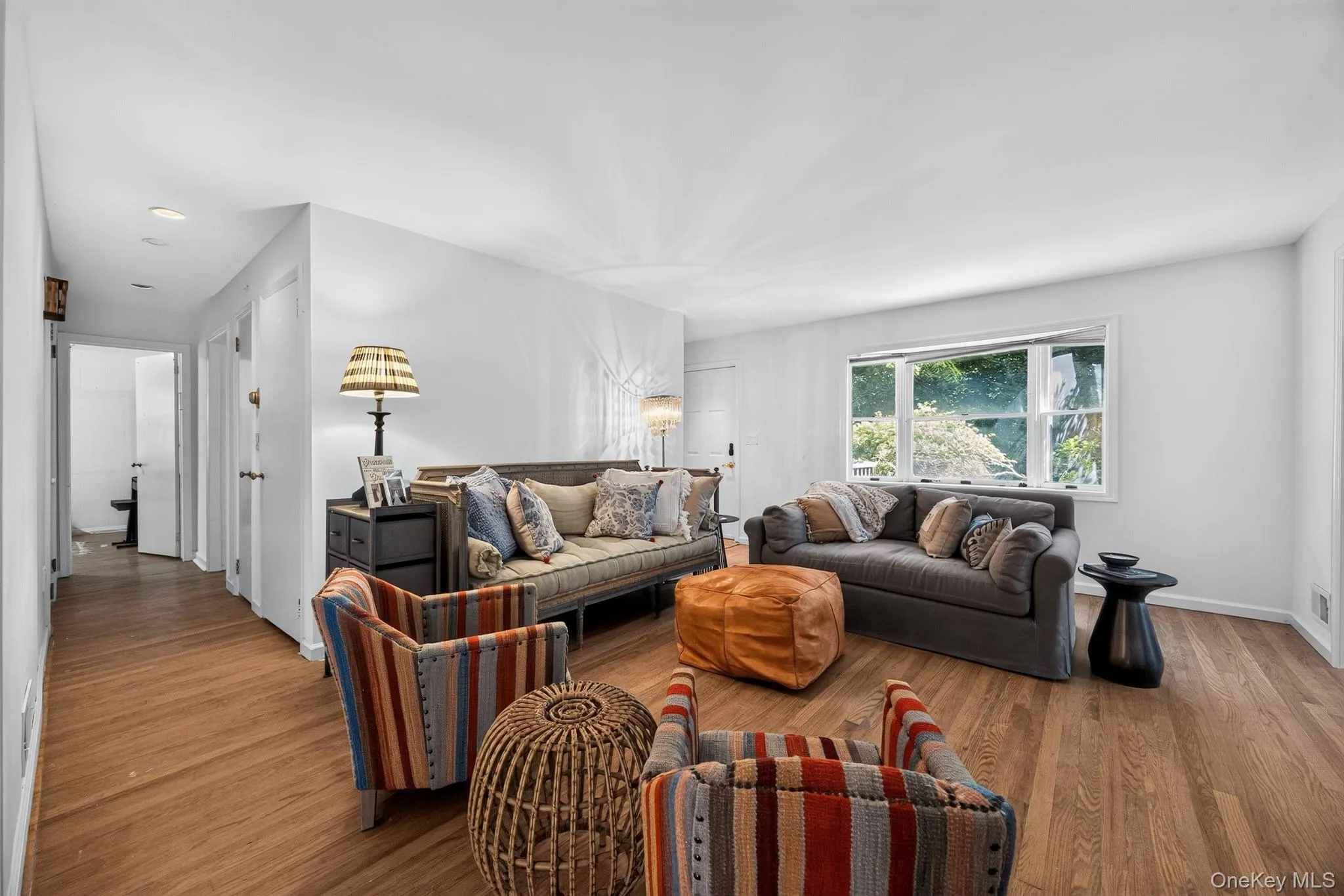 Wood-finish flooring throughout, white painted walls, and a large window with white trim Wood-finish flooring throughout, white painted walls, and a large window with white trim