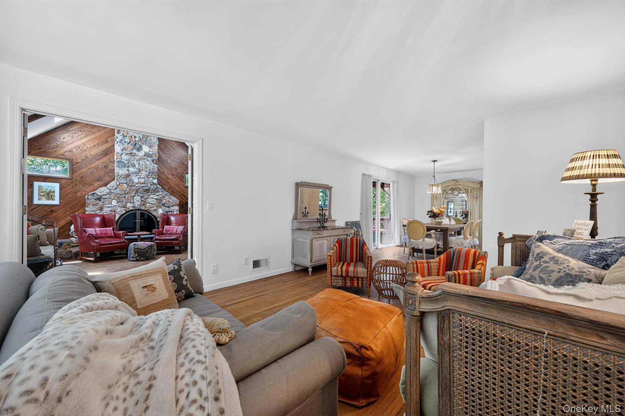 Wood-finish flooring, white walls, and a stone-faced fireplace with a hearth Wood-finish flooring, white walls, and a stone-faced fireplace with a hearth