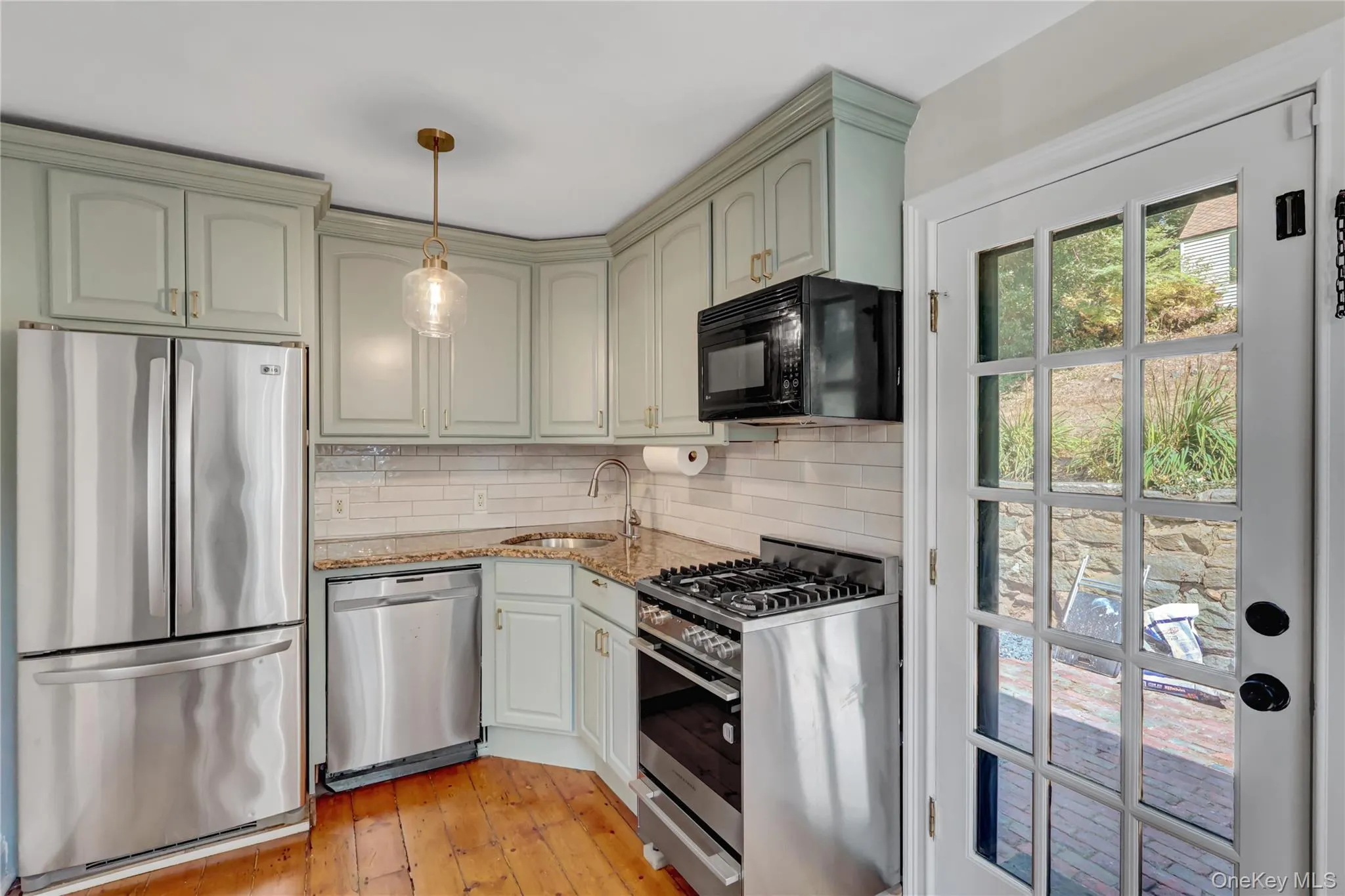 Kitchen with stainless steel appliances, light stone countertops, decorative backsplash, pendant lighting, and light wood finished floors Kitchen with stainless steel appliances, light stone countertops, decorative backsplash, pendant lighting, and light wood finished floors