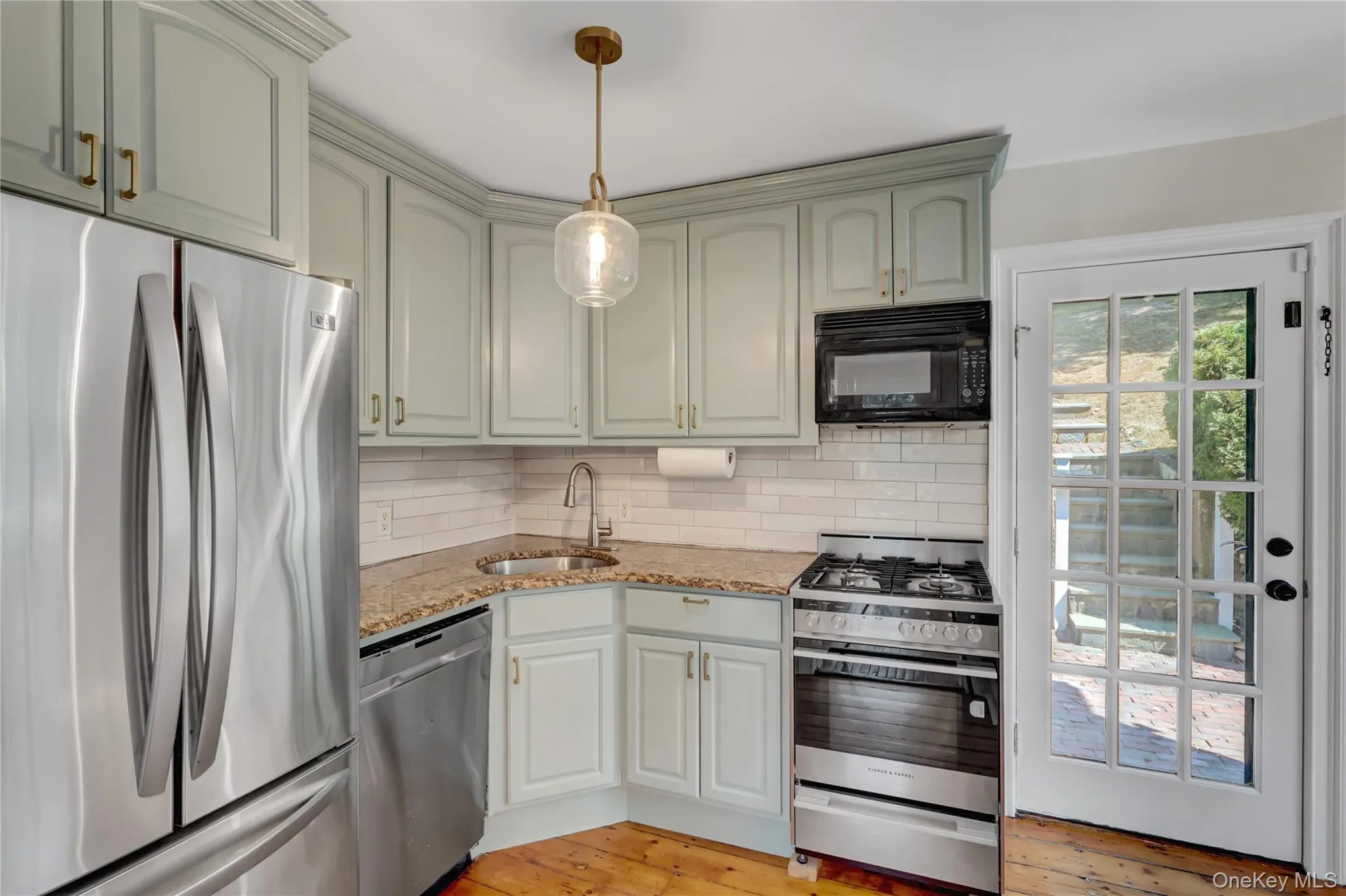 Kitchen with stainless steel appliances, tasteful backsplash, light stone counters, pendant lighting, and light wood-style floors Kitchen with stainless steel appliances, tasteful backsplash, light stone counters, pendant lighting, and light wood-style floors