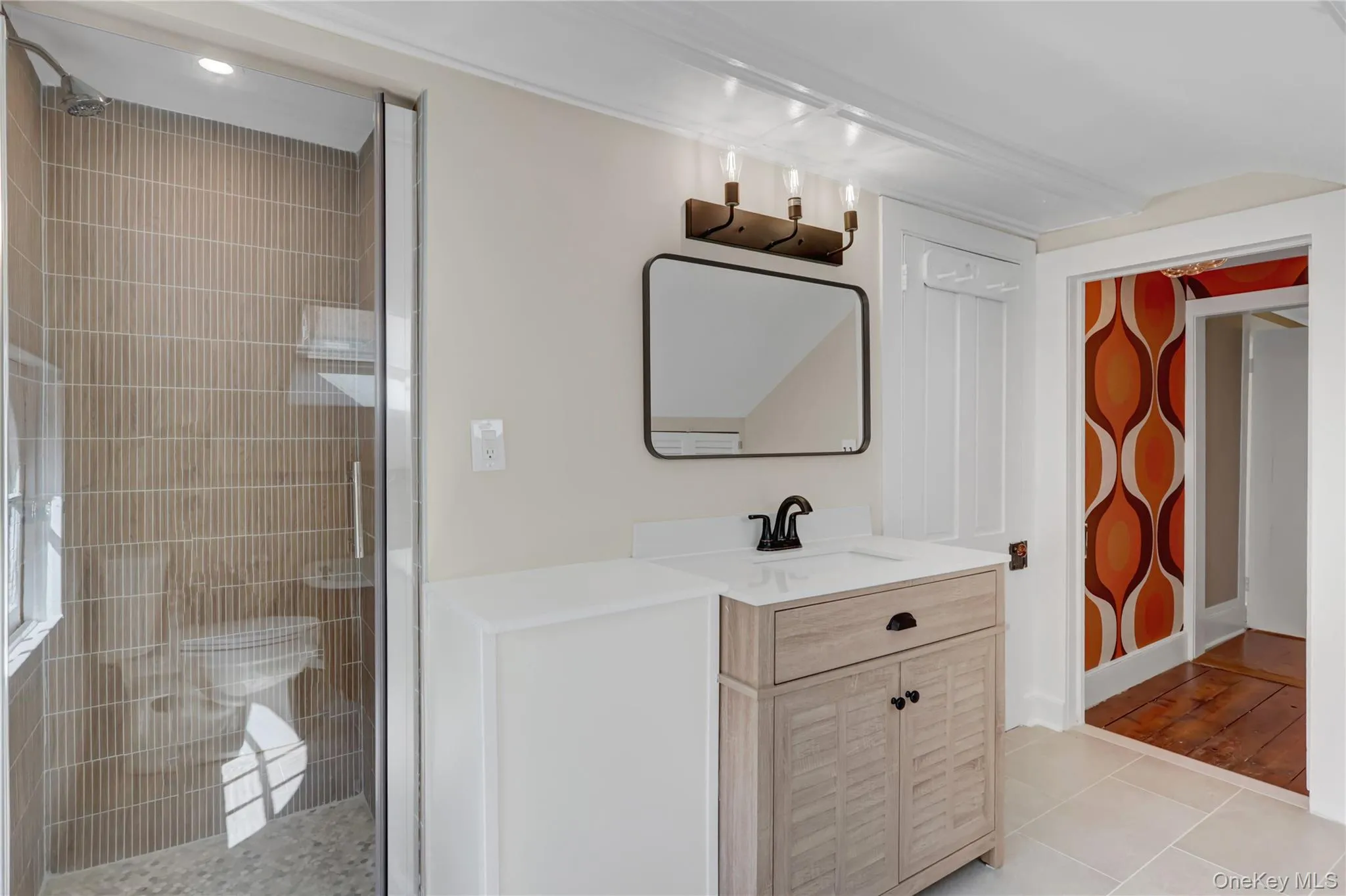 Bathroom featuring a tile shower, vanity, and light tile patterned floors Bathroom featuring a tile shower, vanity, and light tile patterned floors