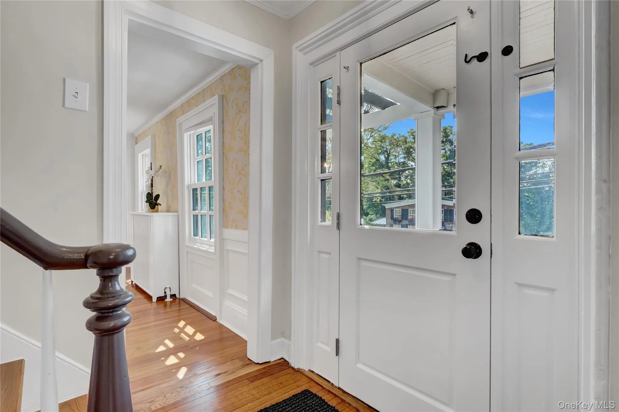 Entryway featuring ornamental molding, a wainscoted wall, light wood finished floors, a decorative wall, and stairway Entryway featuring ornamental molding, a wainscoted wall, light wood finished floors, a decorative wall, and stairway