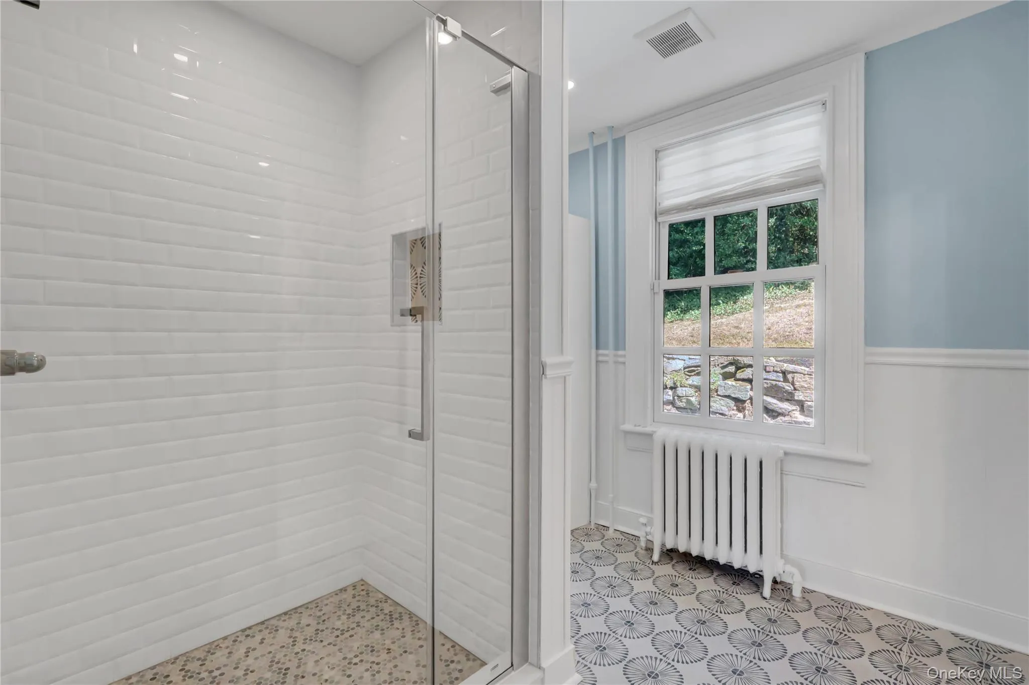 Full bath featuring radiator heating unit and a shower stall Full bath featuring radiator heating unit and a shower stall