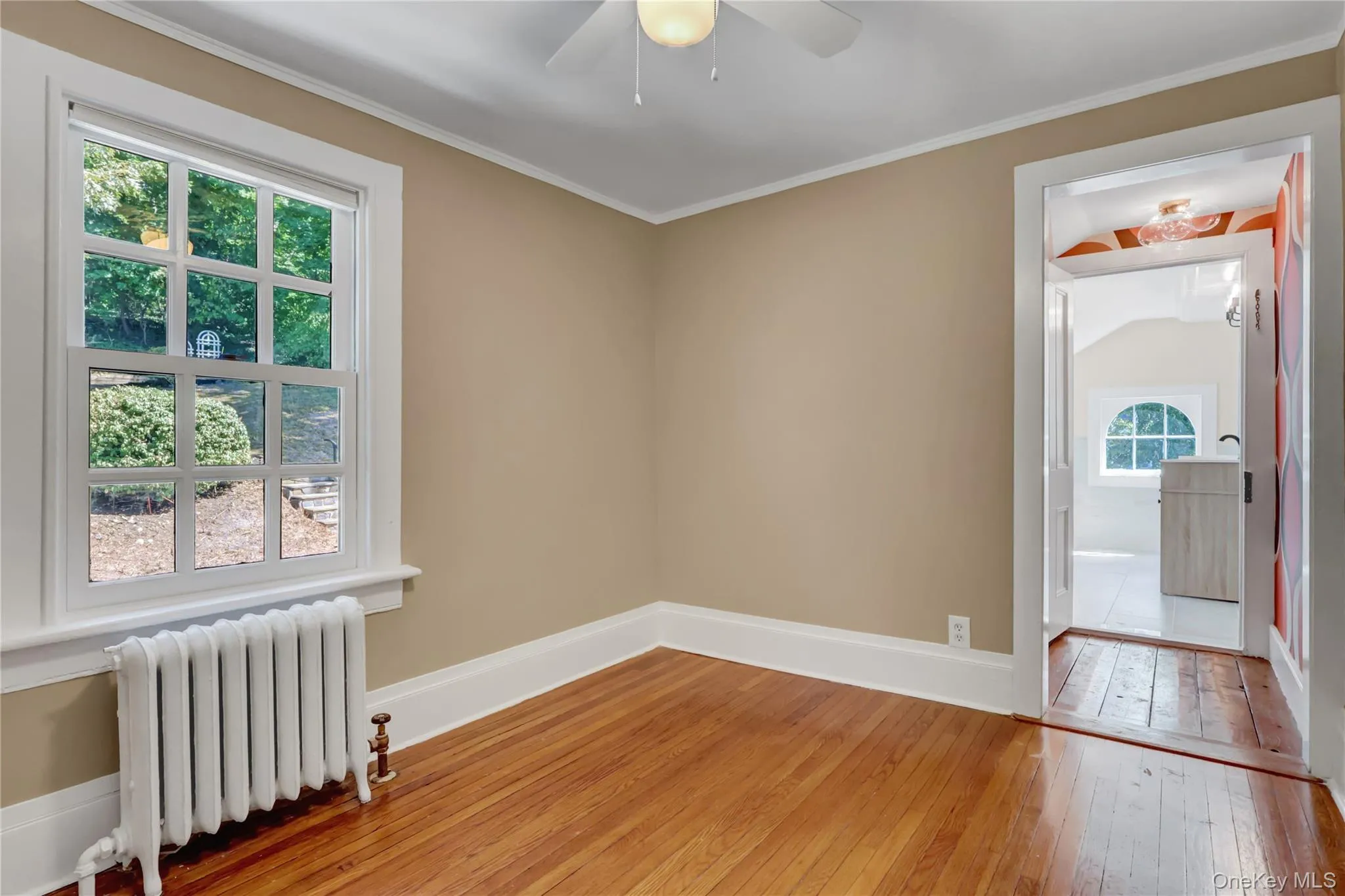 Unfurnished room with radiator, hardwood / wood-style flooring, crown molding, and ceiling fan Unfurnished room with radiator, hardwood / wood-style flooring, crown molding, and ceiling fan