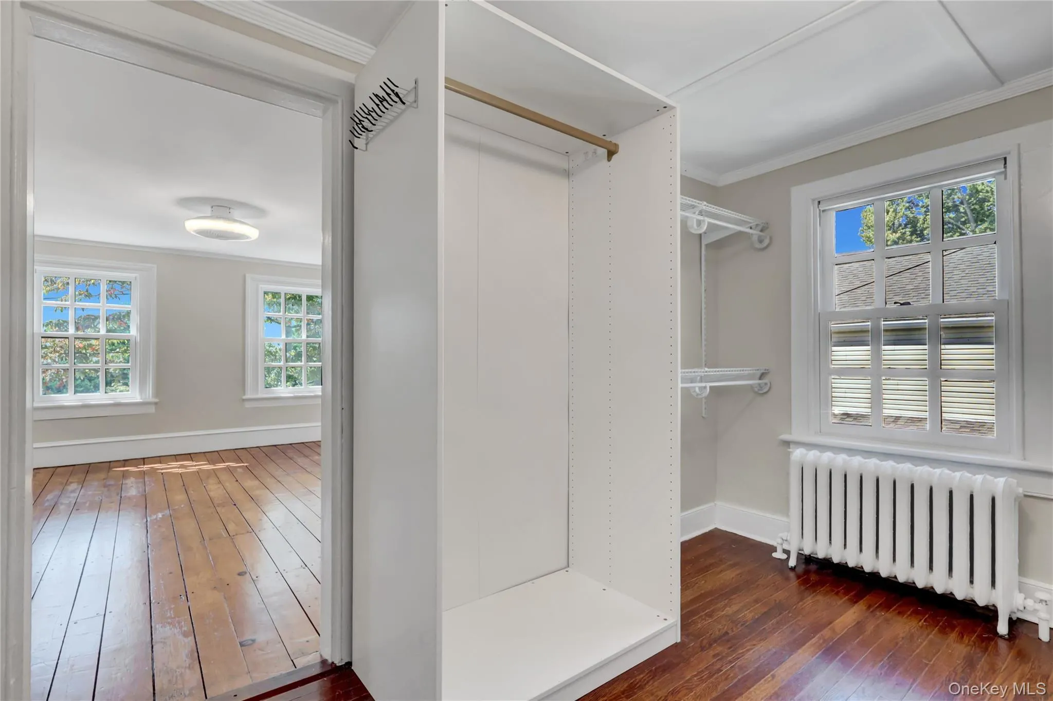 Walk in closet with radiator and dark wood-type flooring Walk in closet with radiator and dark wood-type flooring
