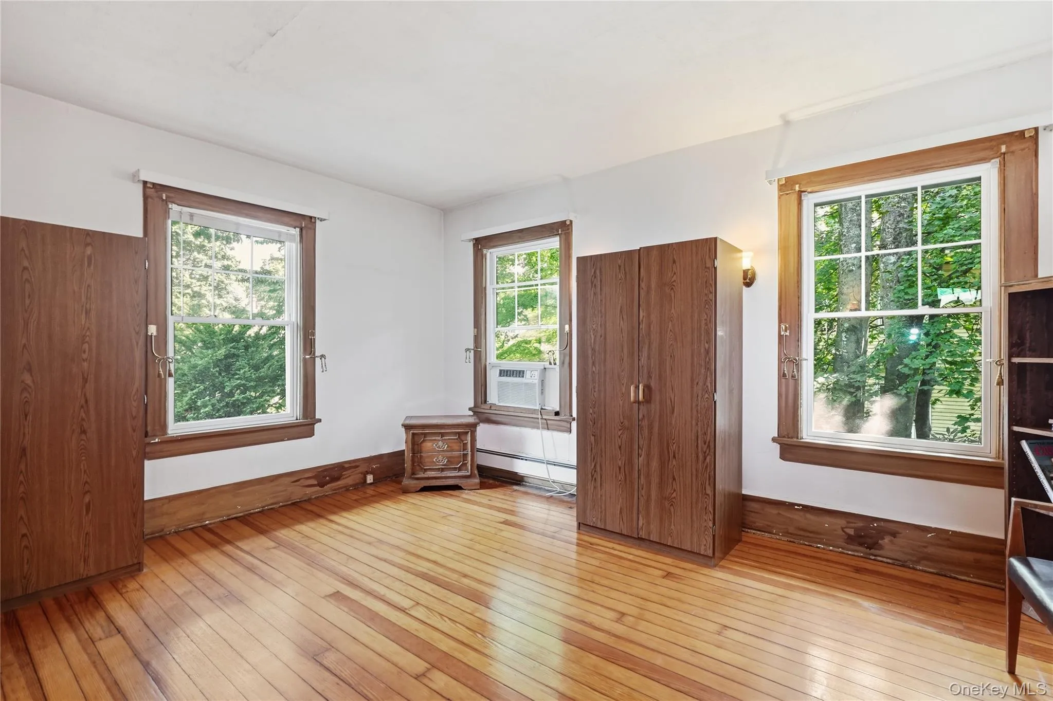 Sun-filled bedroom showcases warm hardwood floors and generous space Sun-filled bedroom showcases warm hardwood floors and generous space