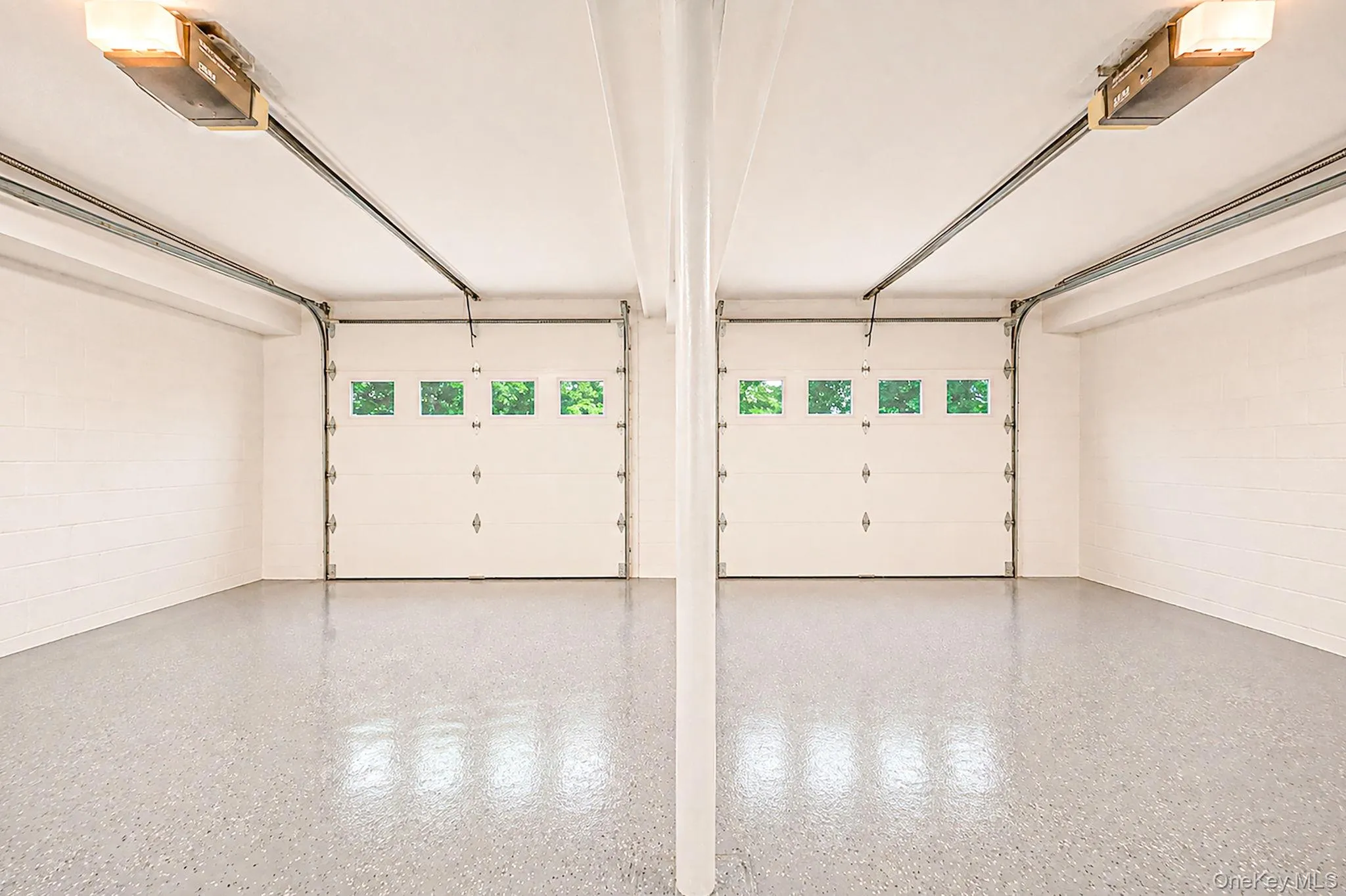 Two garage bays featuring white overhead doors with window inserts and automatic openers Two garage bays featuring white overhead doors with window inserts and automatic openers