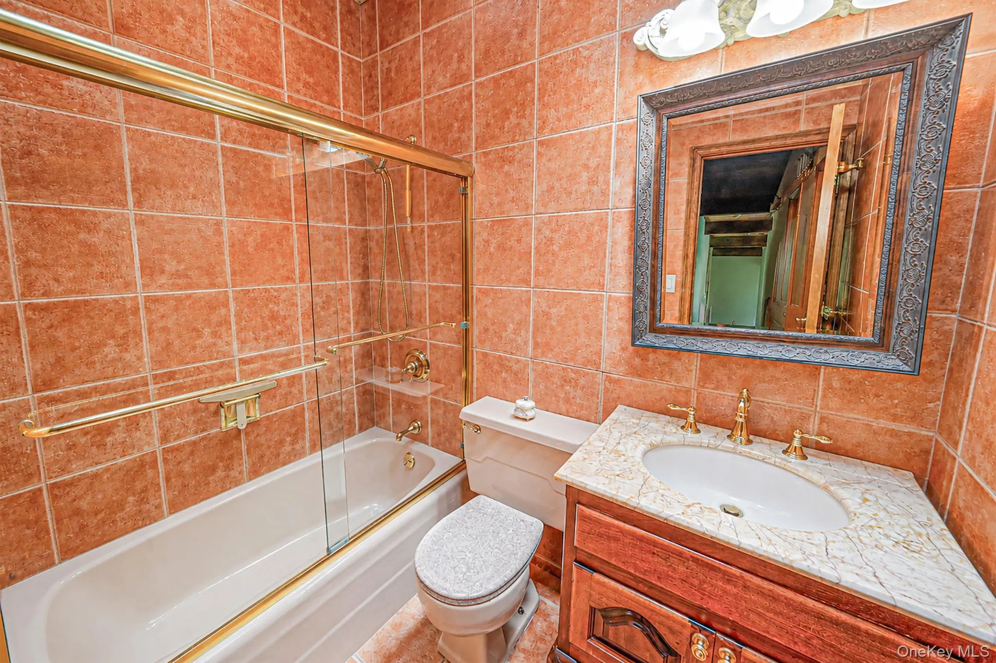 Bathroom featuring a shower/tub combination with glass enclosure, a vanity with an integrated sink and countertop, and a toilet Bathroom featuring a shower/tub combination with glass enclosure, a vanity with an integrated sink and countertop, and a toilet