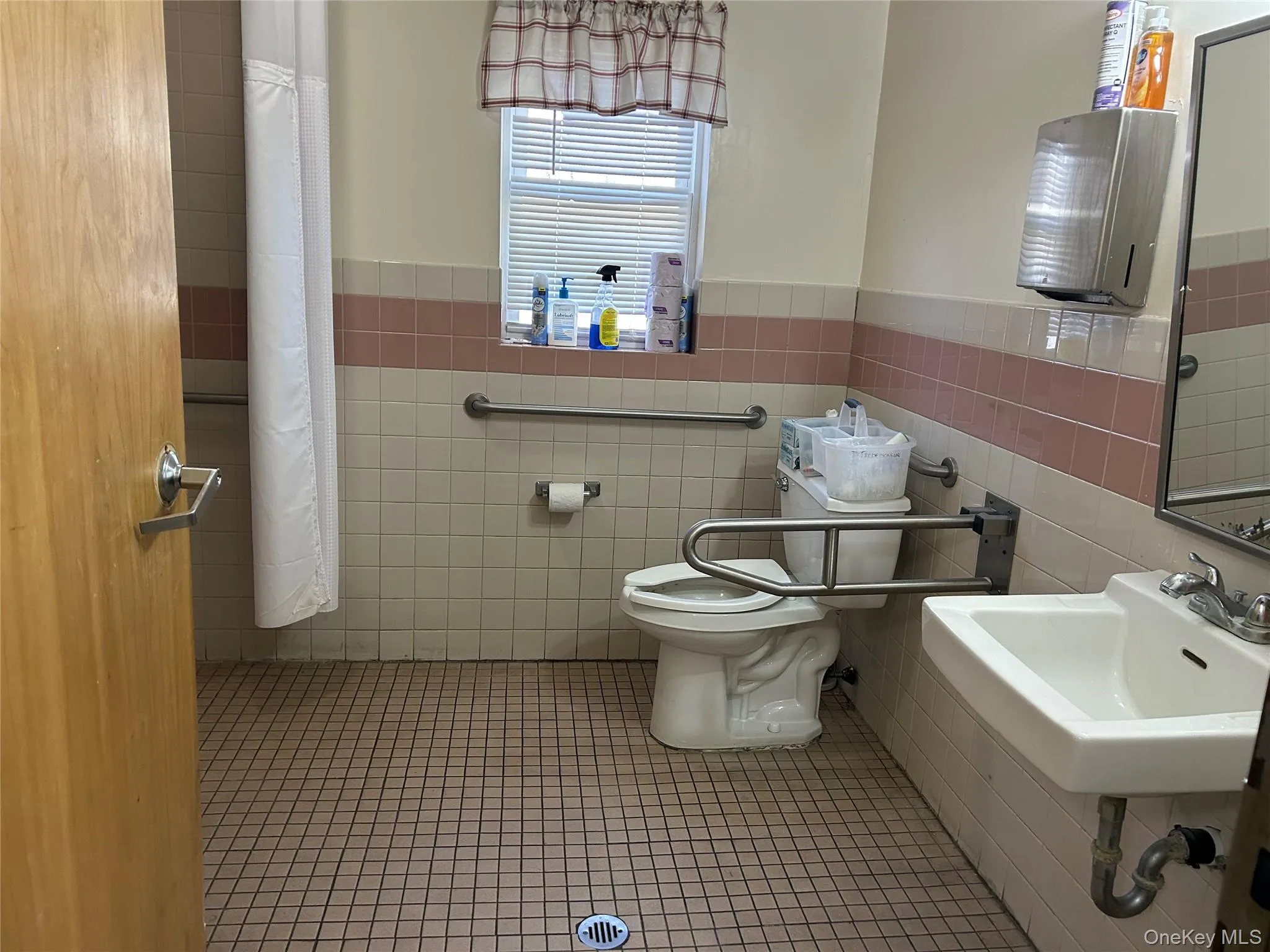 Bathroom featuring tile patterned flooring, a wainscoted wall, and tile walls Bathroom featuring tile patterned flooring, a wainscoted wall, and tile walls