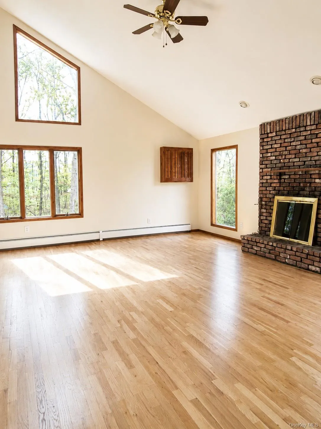 Vaulted ceiling, wood-finish flooring, brick fireplace, and large windows Vaulted ceiling, wood-finish flooring, brick fireplace, and large windows
