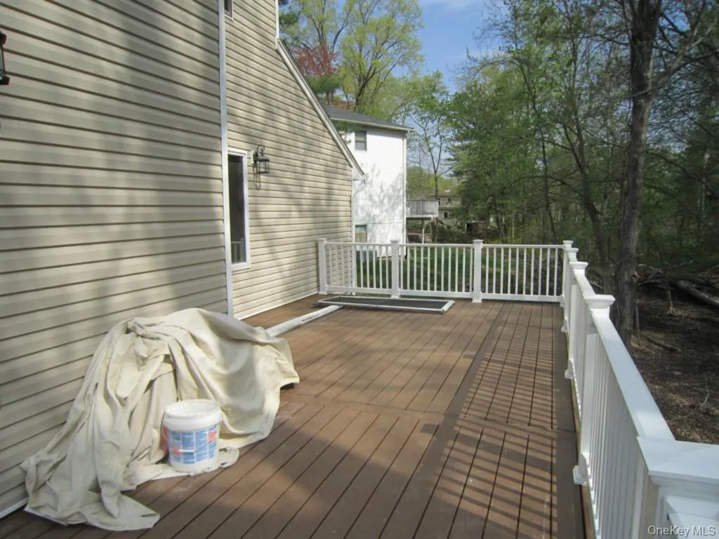 Spacious deck with composite decking and white railing, featuring exterior siding and mature trees Spacious deck with composite decking and white railing, featuring exterior siding and mature trees