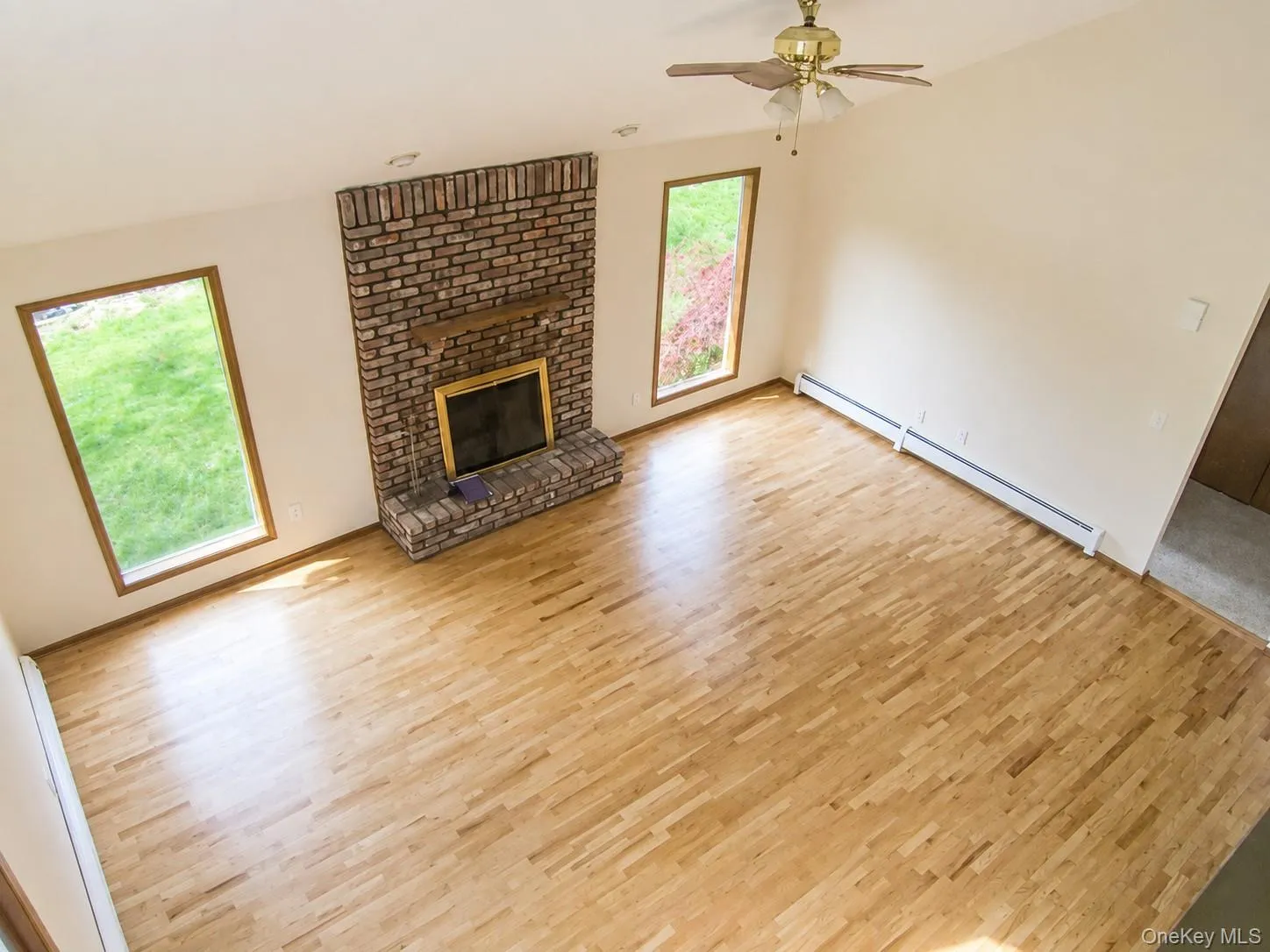 The generously sized living room features vaulted ceilings with a ceiling fan, a wood burning brick fireplace, oak floors and lots of windows The generously sized living room features vaulted ceilings with a ceiling fan, a wood burning brick fireplace, oak floors and lots of windows