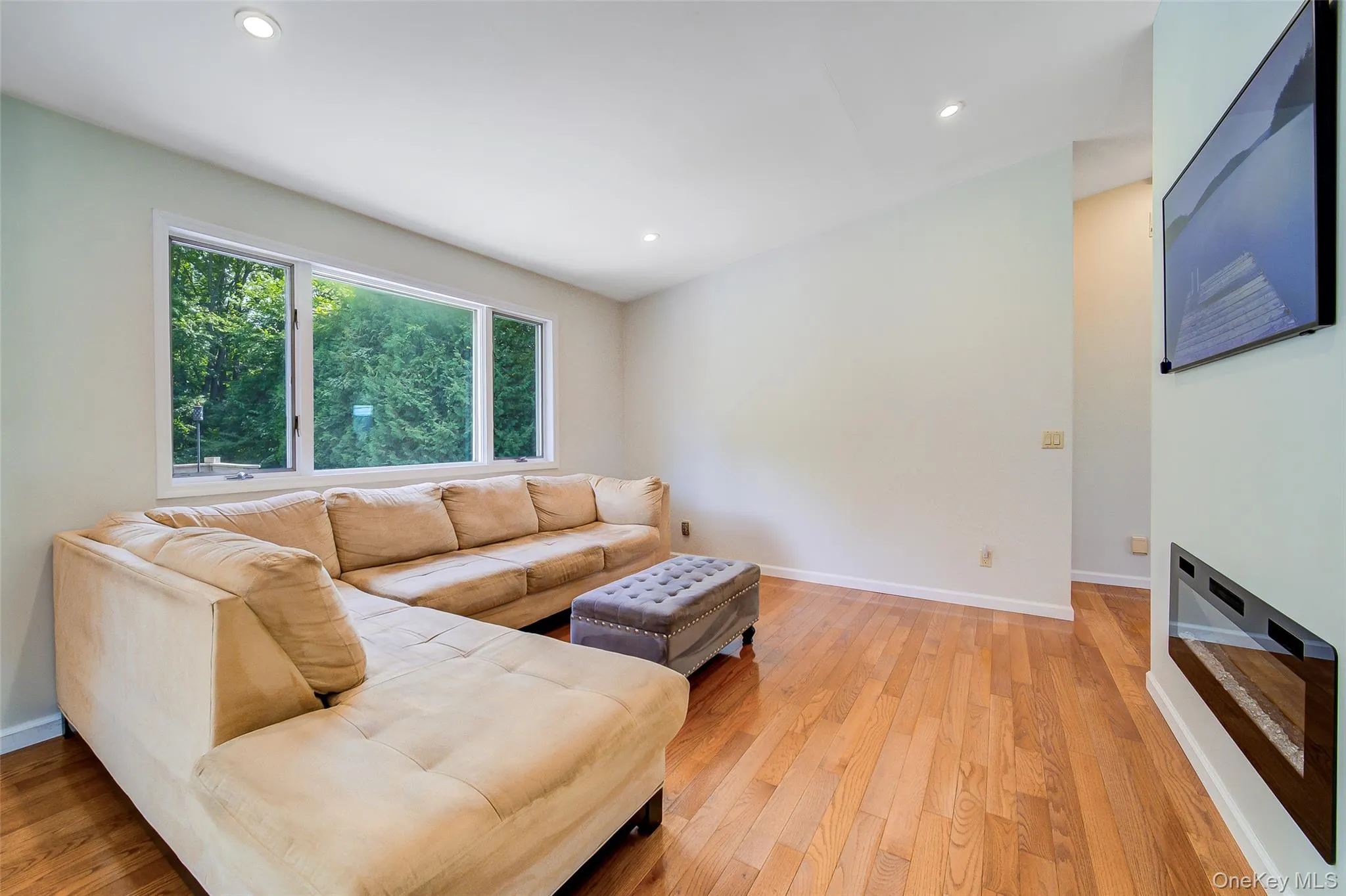 Hardwood flooring, recessed lighting, large picture windows, and a built-in wall fireplace Hardwood flooring, recessed lighting, large picture windows, and a built-in wall fireplace