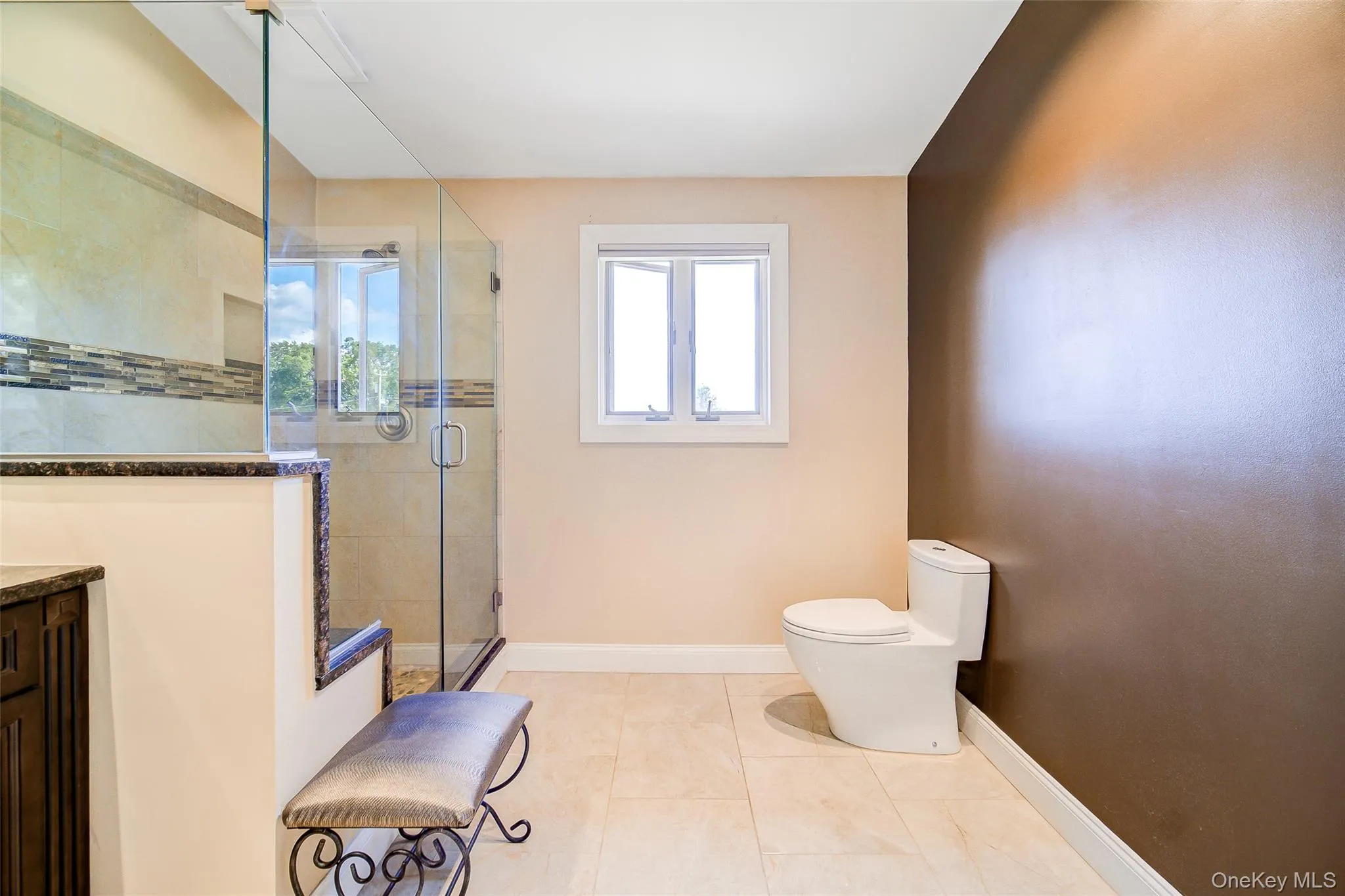 Glass-enclosed shower with tiled walls and a decorative mosaic band Glass-enclosed shower with tiled walls and a decorative mosaic band