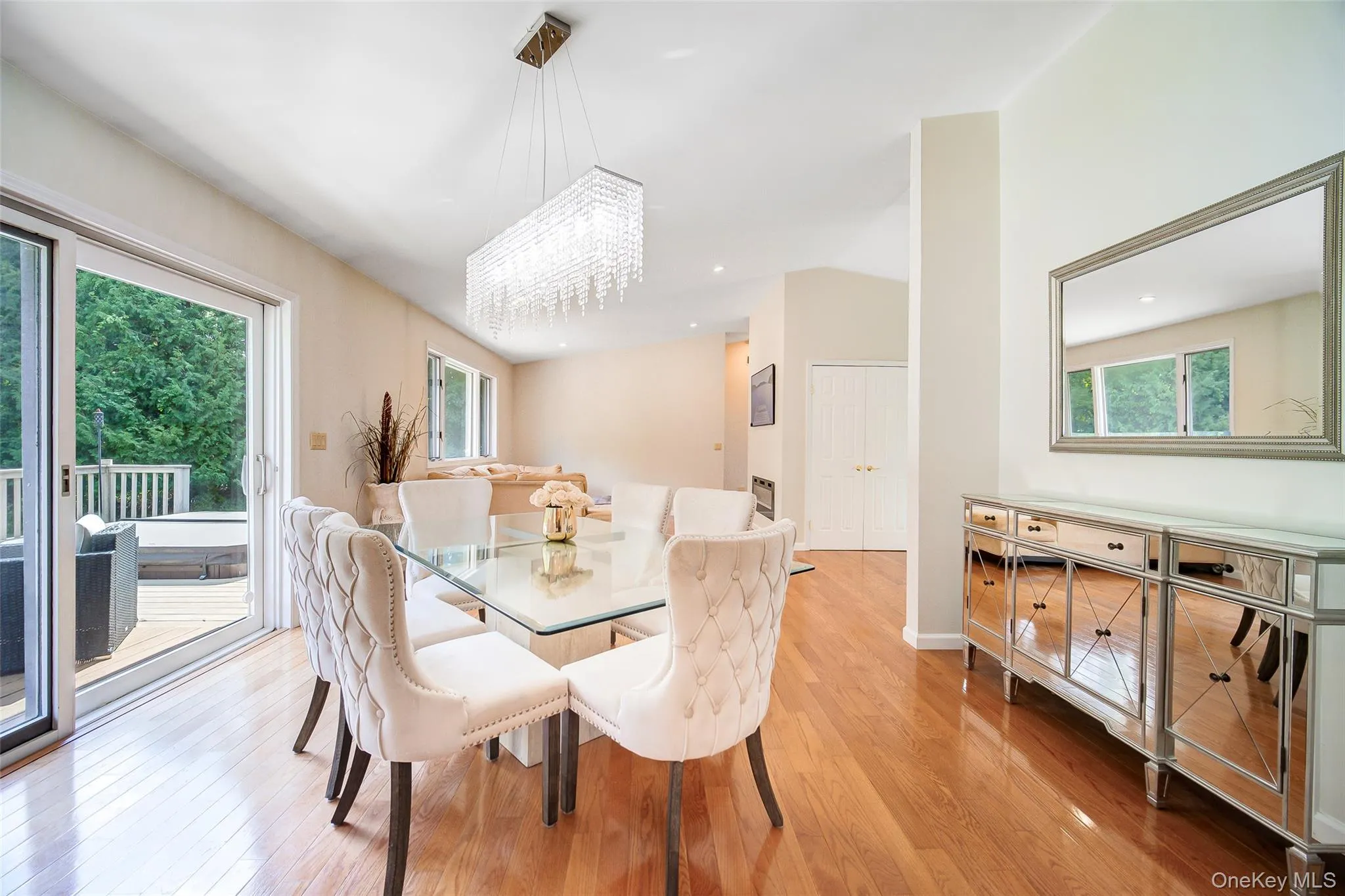 Hardwood flooring throughout, sliding glass door to exterior deck, contemporary rectangular chandelier, mirrored console table, and vaulted ceiling Hardwood flooring throughout, sliding glass door to exterior deck, contemporary rectangular chandelier, mirrored console table, and vaulted ceiling