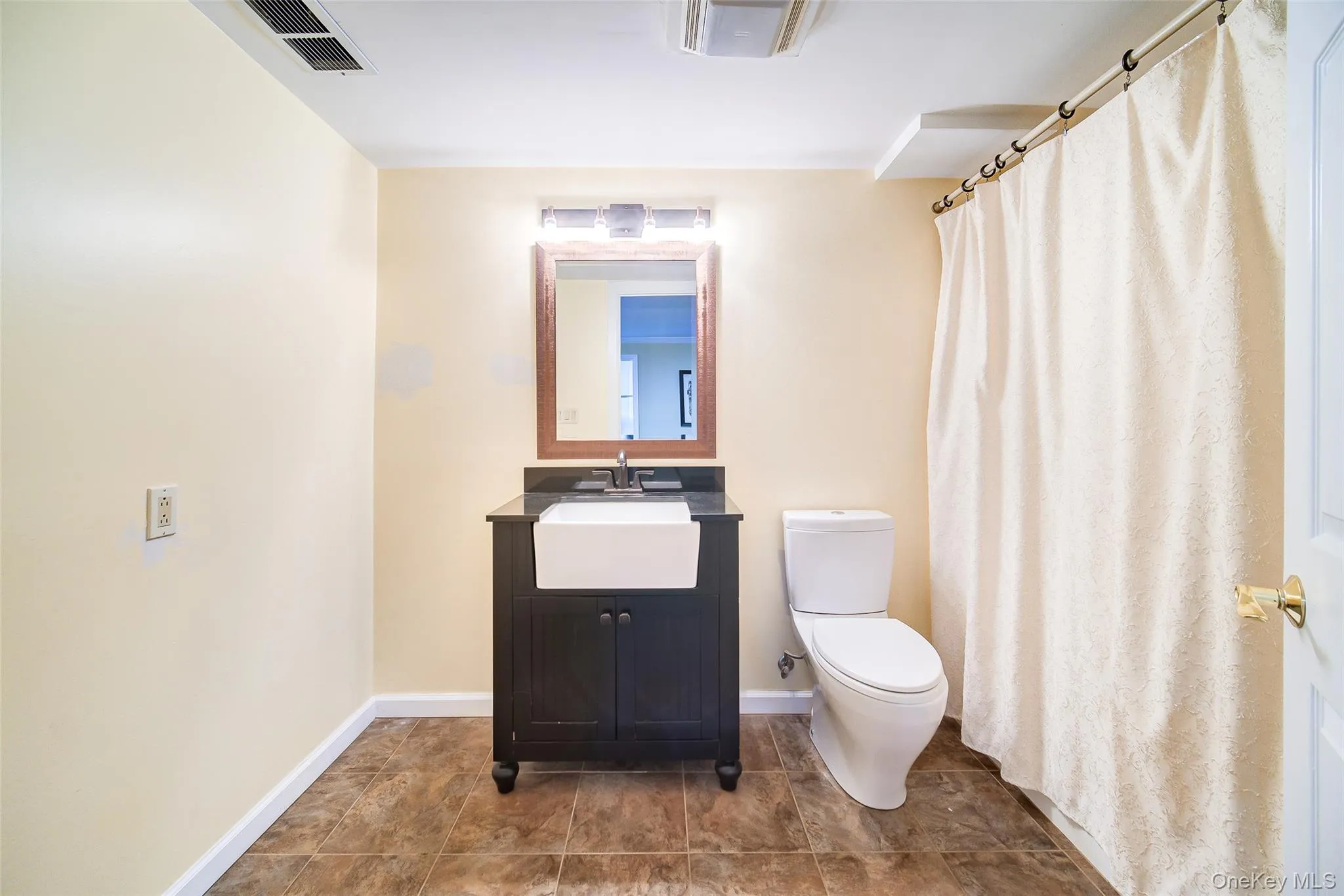 Dark wood vanity with a white vessel sink, dark countertop, and a wood-framed mirror Dark wood vanity with a white vessel sink, dark countertop, and a wood-framed mirror