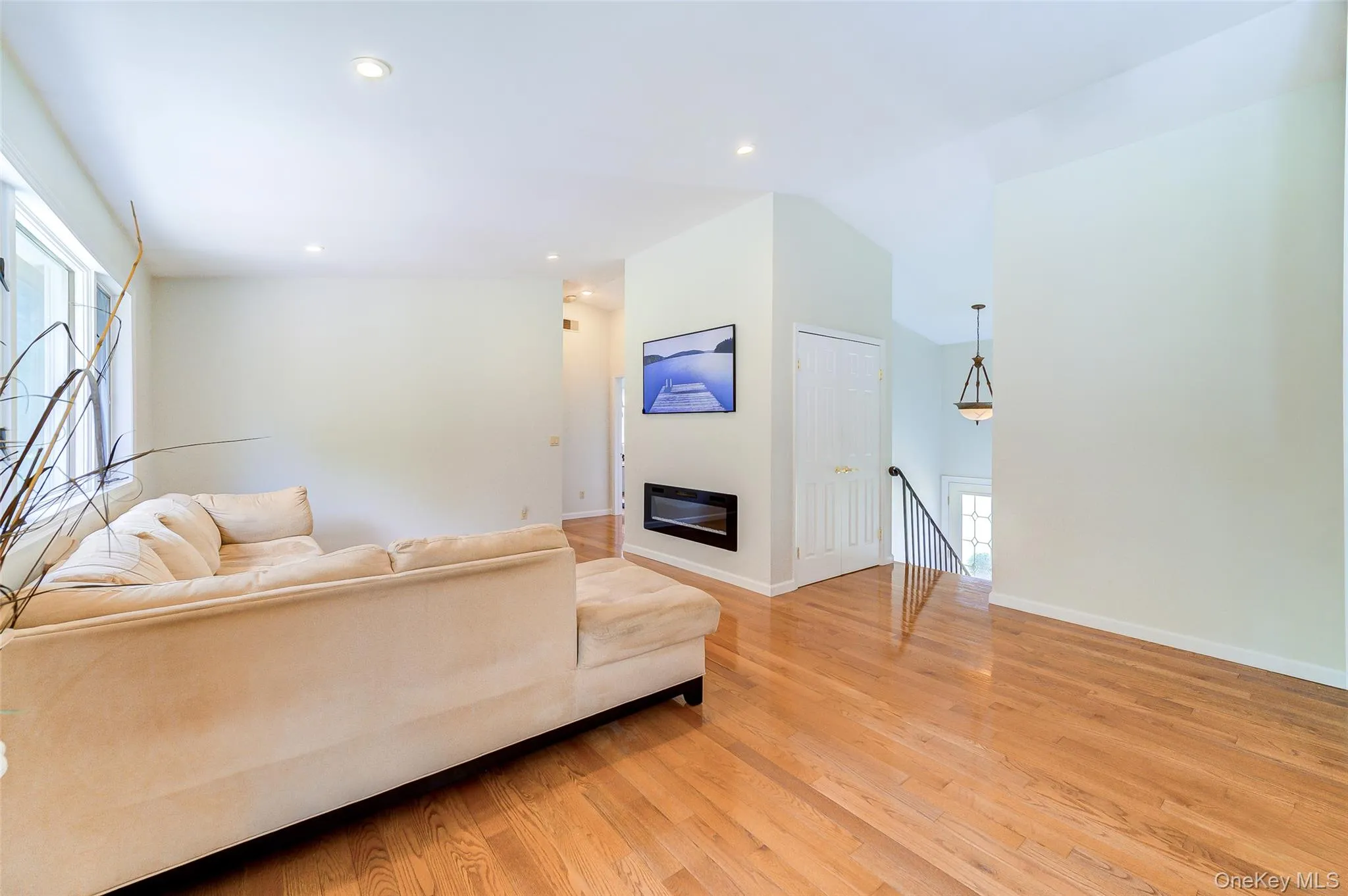 Recessed lighting, wood-finish flooring, built-in electric fireplace, white interior doors, and a wrought iron stair railing Recessed lighting, wood-finish flooring, built-in electric fireplace, white interior doors, and a wrought iron stair railing