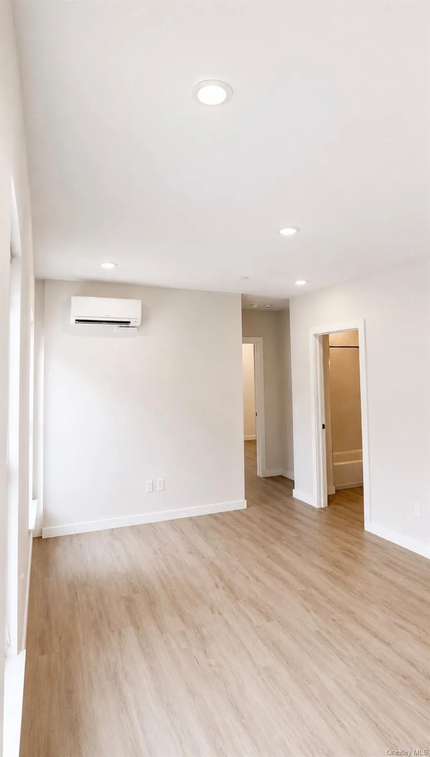 Recessed lighting, wood-finish flooring, white walls, mini-split air conditioning unit, white trim Recessed lighting, wood-finish flooring, white walls, mini-split air conditioning unit, white trim