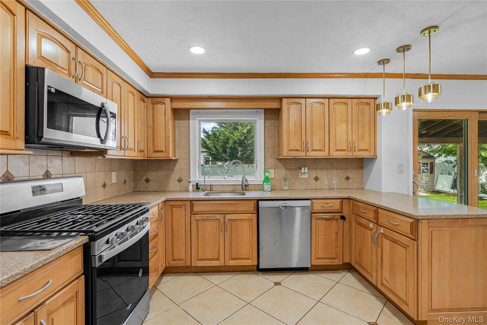 Kitchen featuring natural wood-finish cabinetry, stainless steel appliances, tiled flooring, and recessed lighting Kitchen featuring natural wood-finish cabinetry, stainless steel appliances, tiled flooring, and recessed lighting