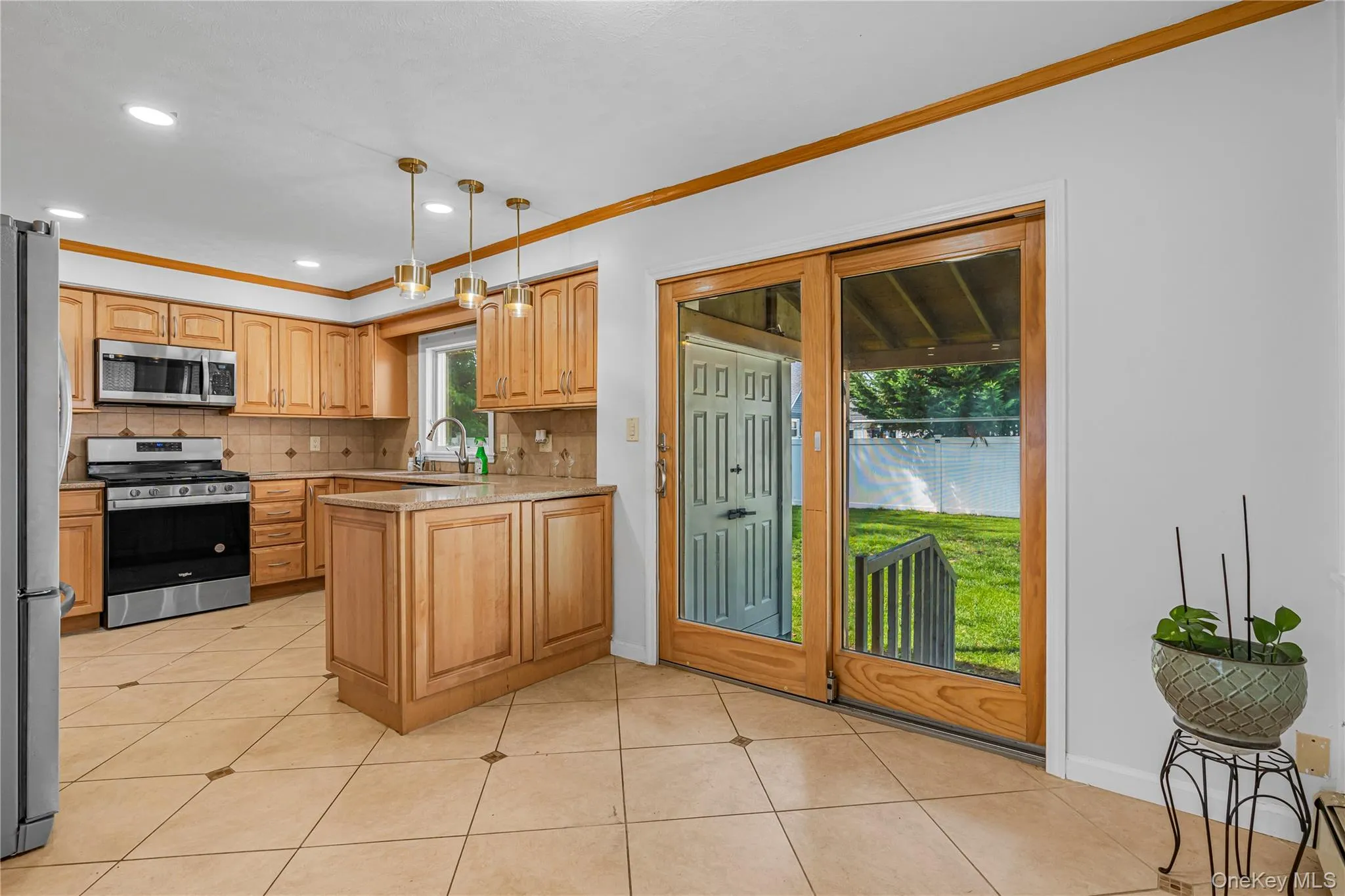 Kitchen featuring wood-finish cabinetry, stainless steel appliances, a center island, and tile flooring Kitchen featuring wood-finish cabinetry, stainless steel appliances, a center island, and tile flooring