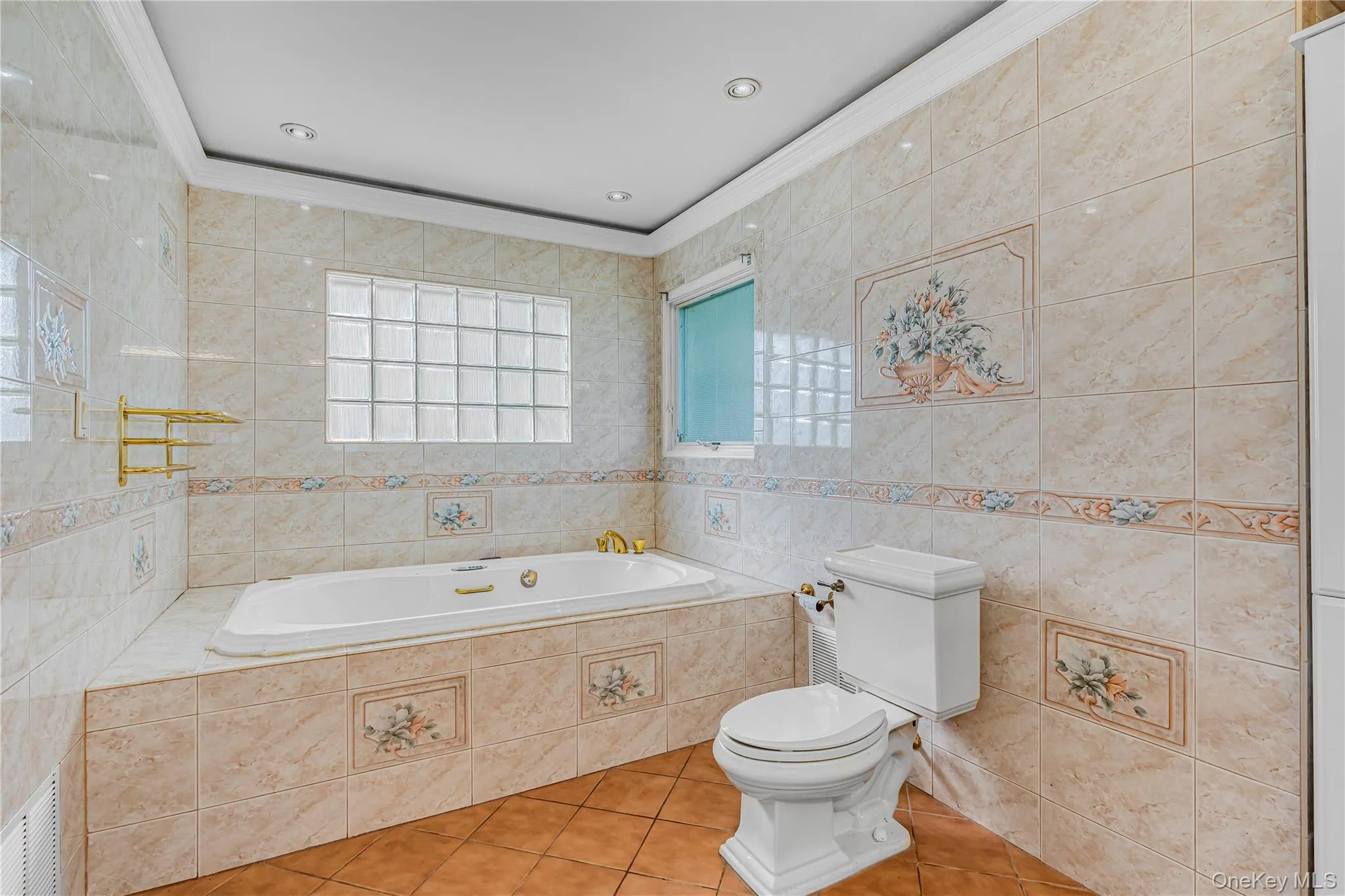Tile-surrounded soaking tub, glass block window, recessed lighting, and wall-mounted towel rack Tile-surrounded soaking tub, glass block window, recessed lighting, and wall-mounted towel rack