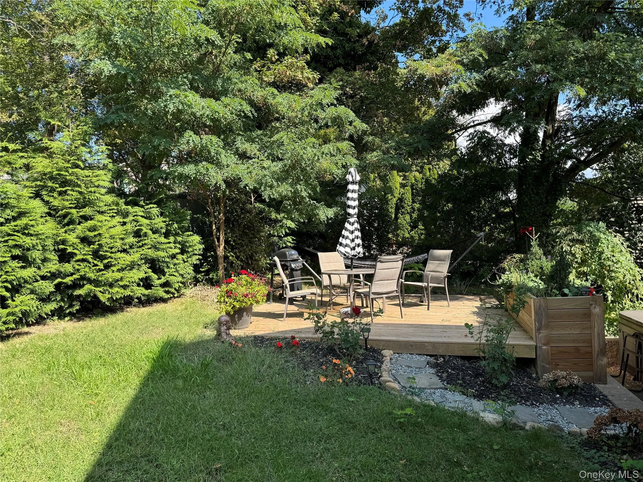 View of green lawn featuring a deck and view of wooded area View of green lawn featuring a deck and view of wooded area
