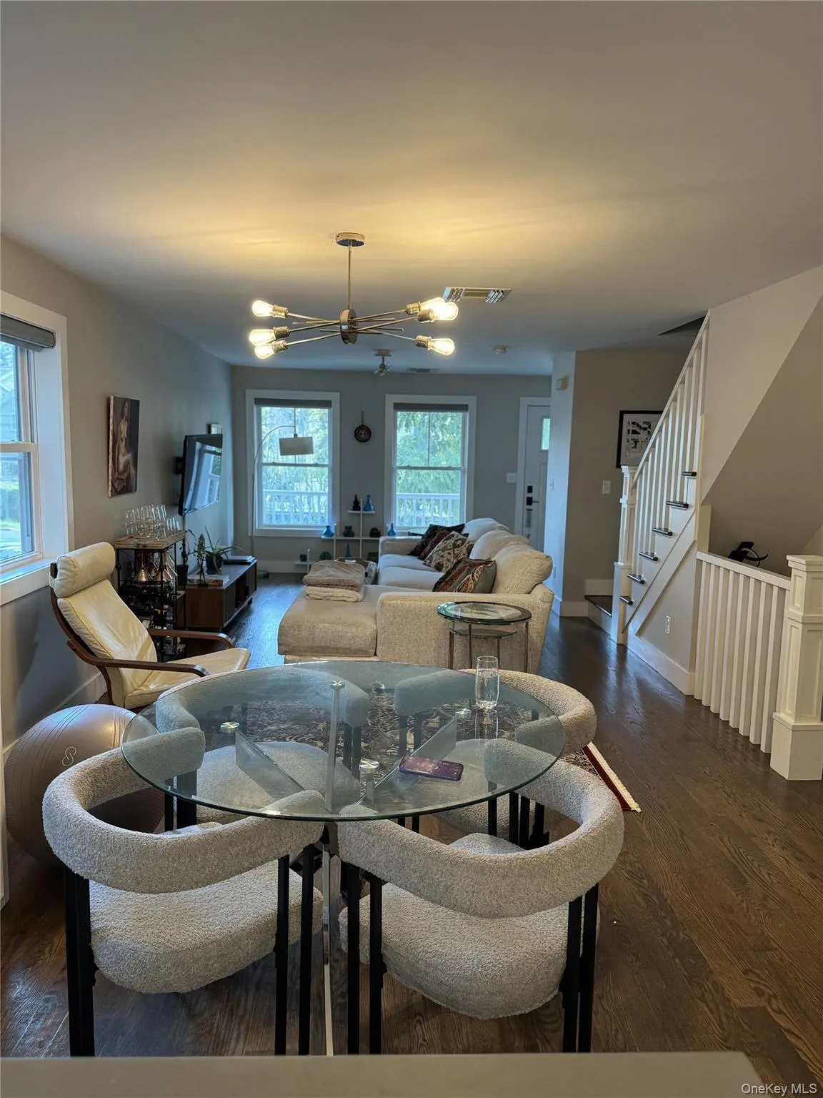 Living room with dark wood-style flooring, stairs, and a chandelier Living room with dark wood-style flooring, stairs, and a chandelier