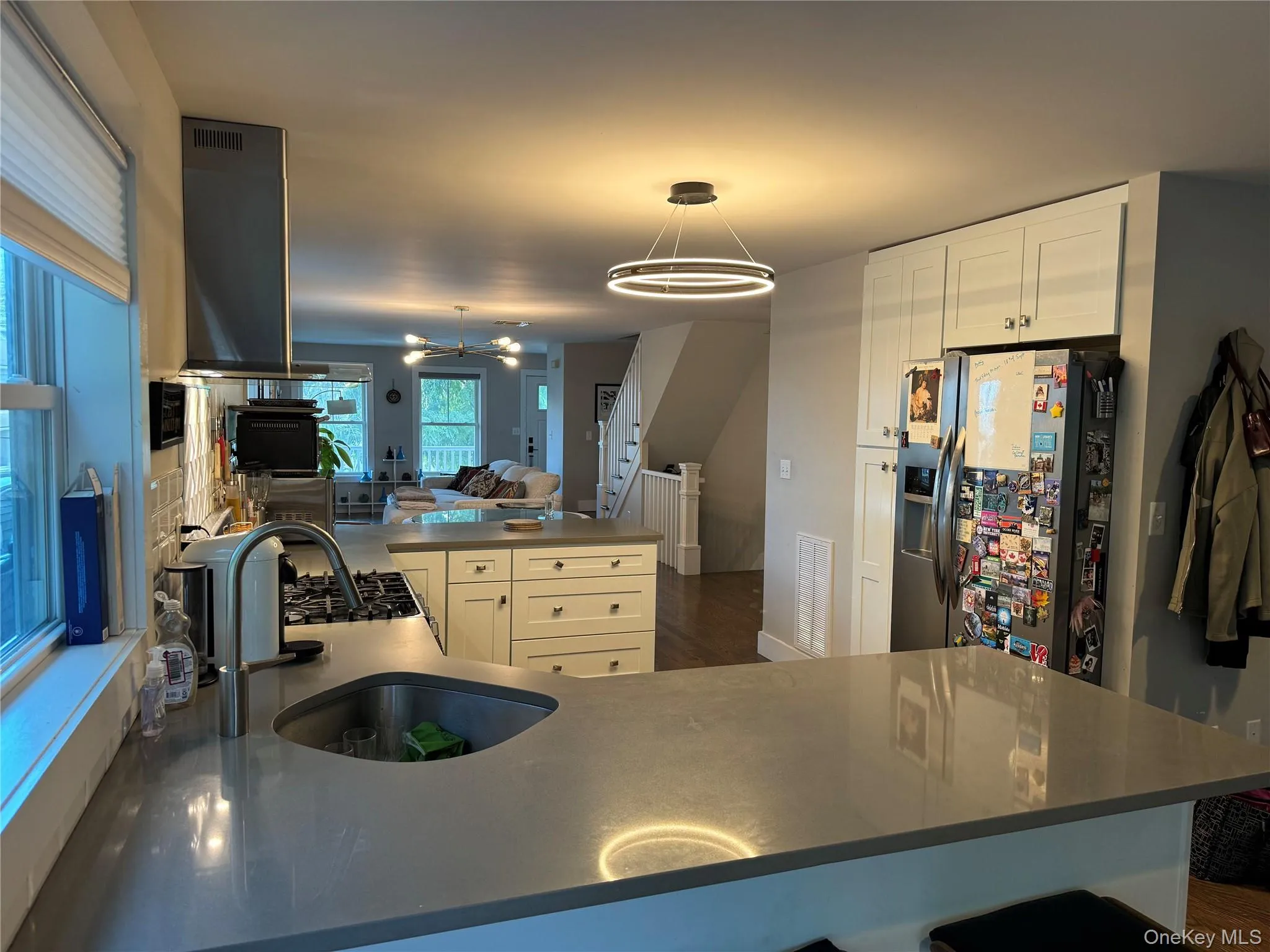 Kitchen featuring stainless steel fridge, open floor plan, white cabinetry, hanging light fixtures, and a chandelier Kitchen featuring stainless steel fridge, open floor plan, white cabinetry, hanging light fixtures, and a chandelier