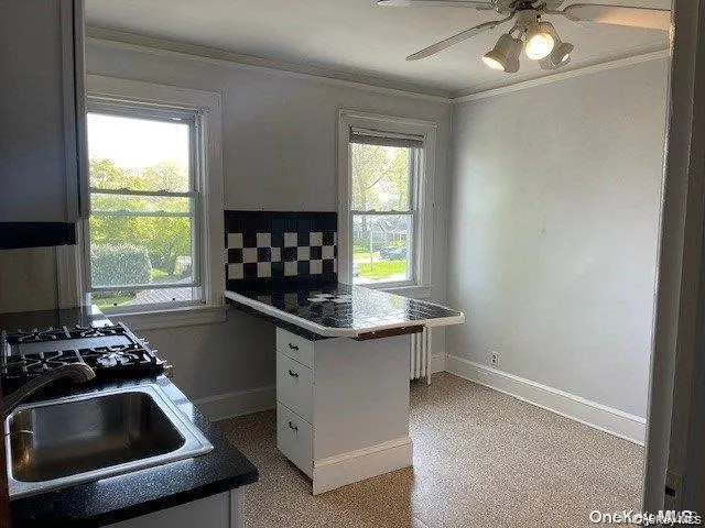 Kitchen featuring a built-in range, stainless steel sink, black quartz countertops, and a ceiling fan with light fixture Kitchen featuring a built-in range, stainless steel sink, black quartz countertops, and a ceiling fan with light fixture