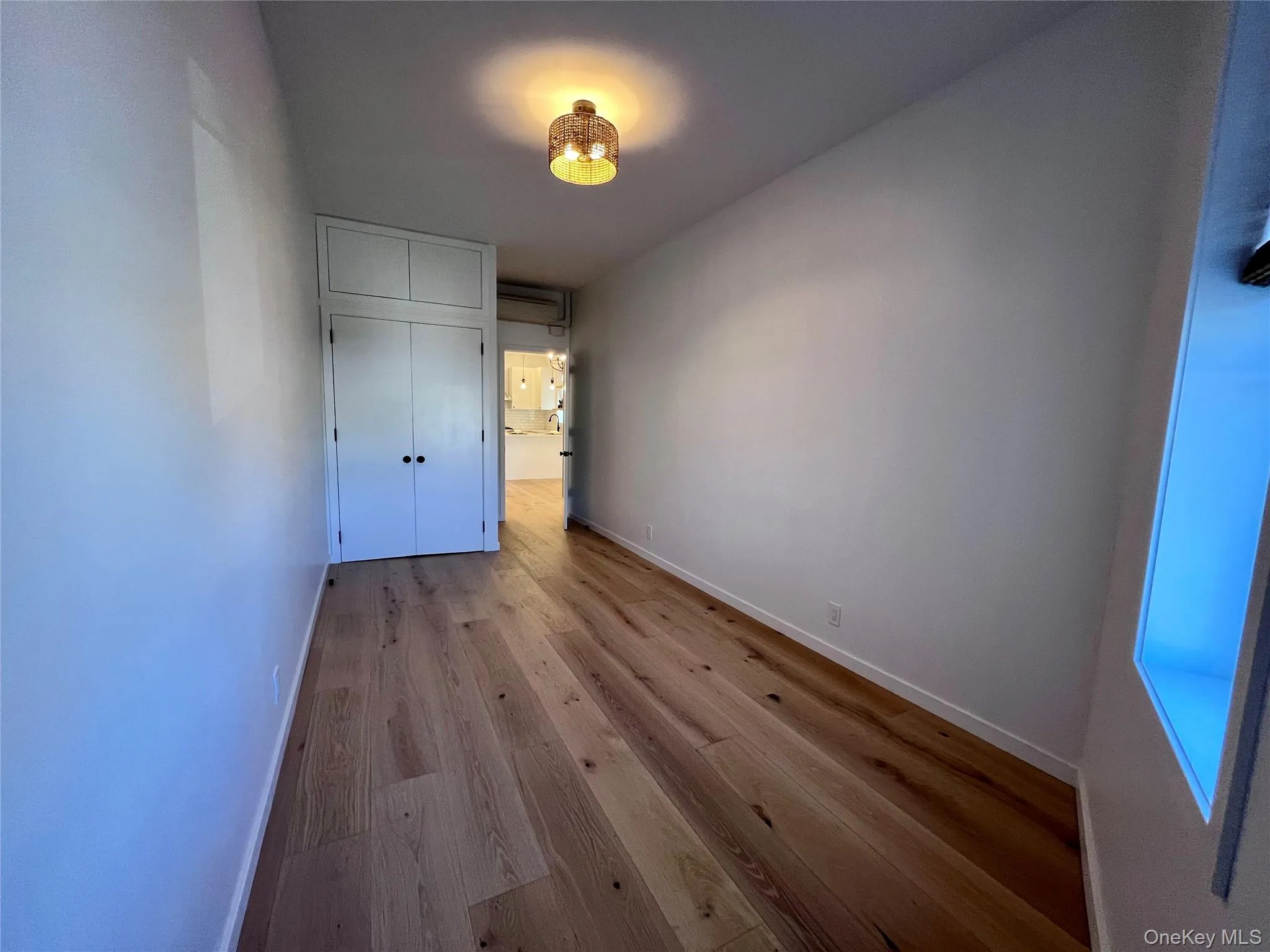 Wood-finish flooring throughout, featuring a built-in closet with upper cabinetry, and recessed wall shelving Wood-finish flooring throughout, featuring a built-in closet with upper cabinetry, and recessed wall shelving