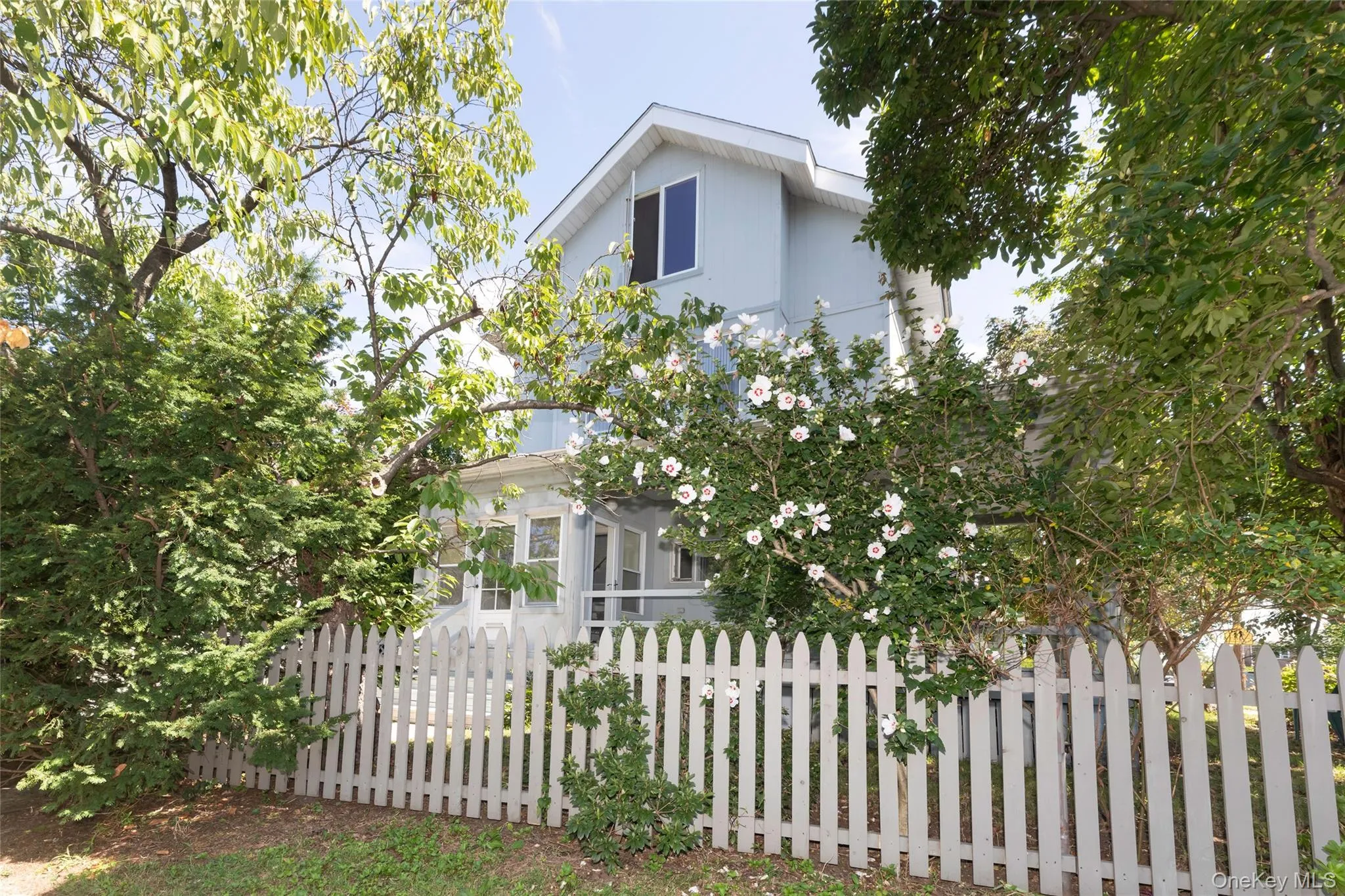Lovely trees with a picket fence surround the home Lovely trees with a picket fence surround the home