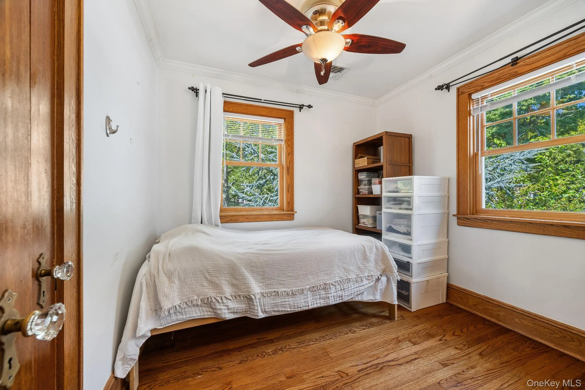 Bedroom with ornamental molding, wood finished floors, and a ceiling fan Bedroom with ornamental molding, wood finished floors, and a ceiling fan
