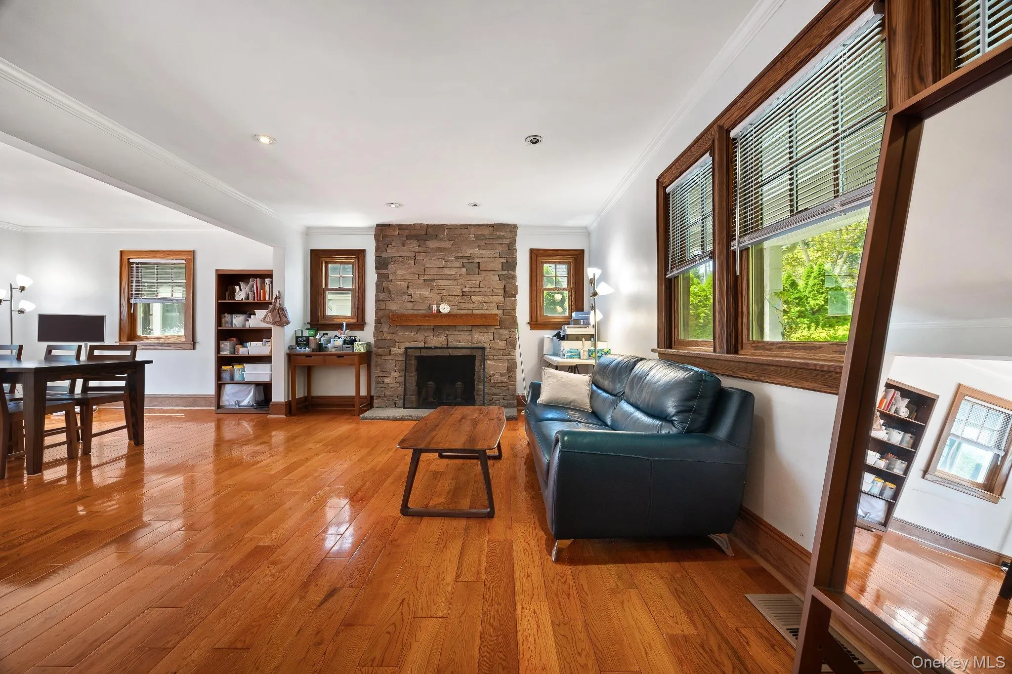 Living room featuring ornamental molding, light wood-type flooring, and a fireplace Living room featuring ornamental molding, light wood-type flooring, and a fireplace