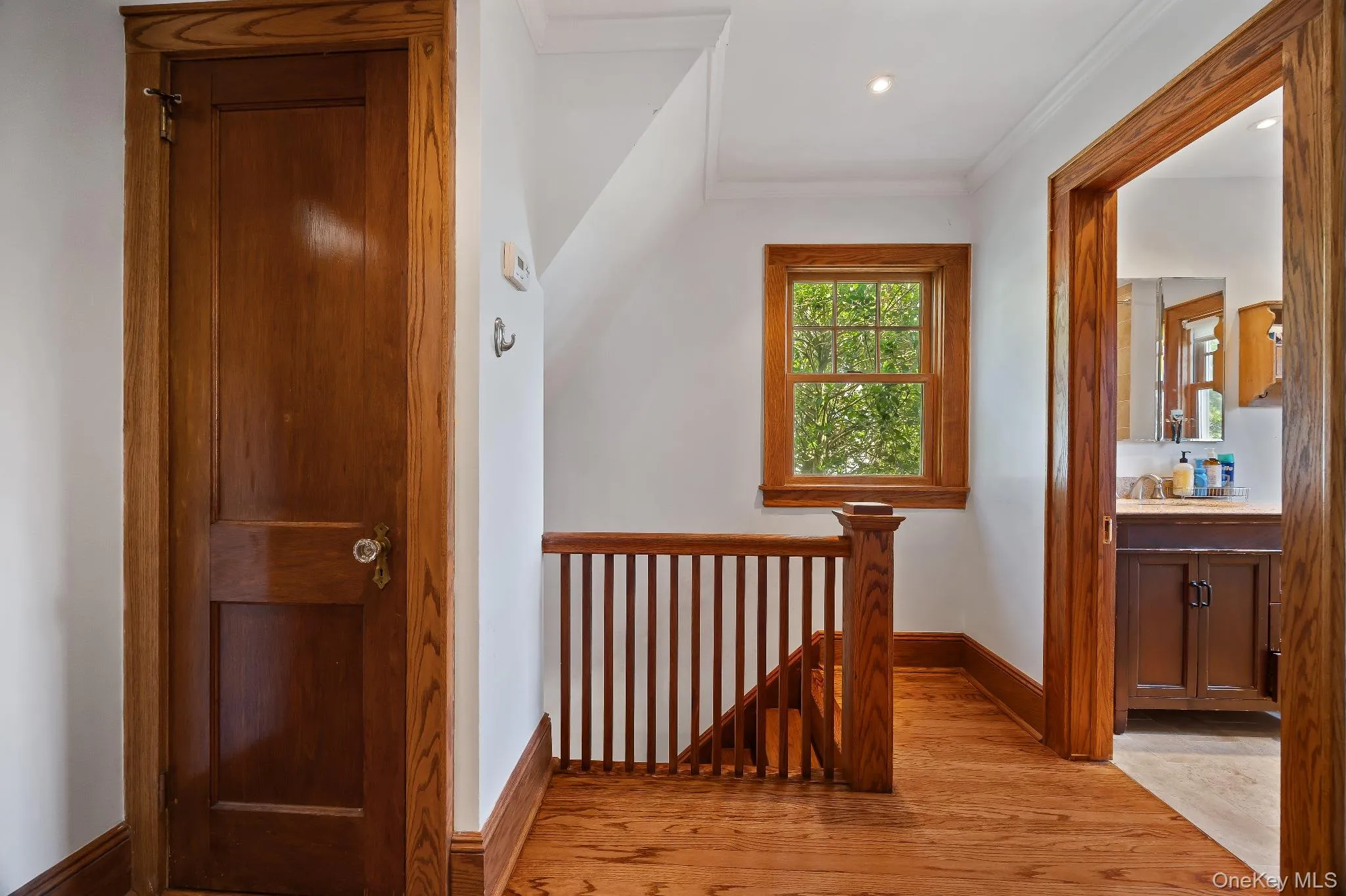 Hallway with an upstairs landing, light wood-type flooring, ornamental molding, and recessed lighting Hallway with an upstairs landing, light wood-type flooring, ornamental molding, and recessed lighting