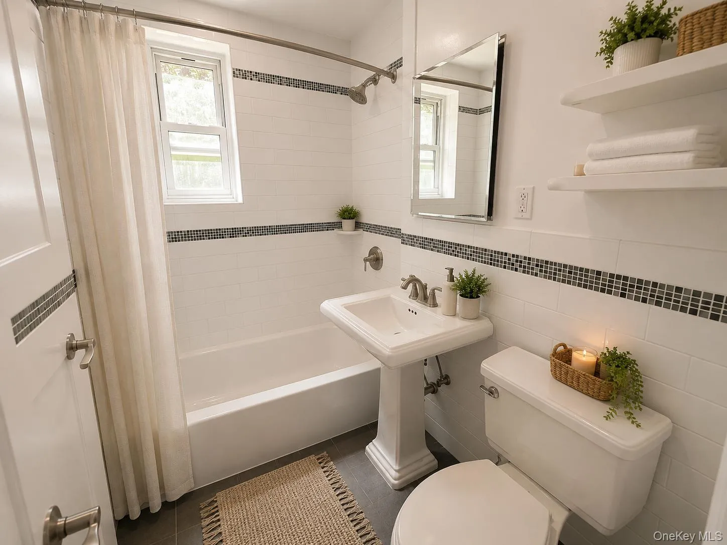 Bathroom featuring a white pedestal sink, white subway tile with mosaic accent, a full-size bathtub, and a window with trim Bathroom featuring a white pedestal sink, white subway tile with mosaic accent, a full-size bathtub, and a window with trim