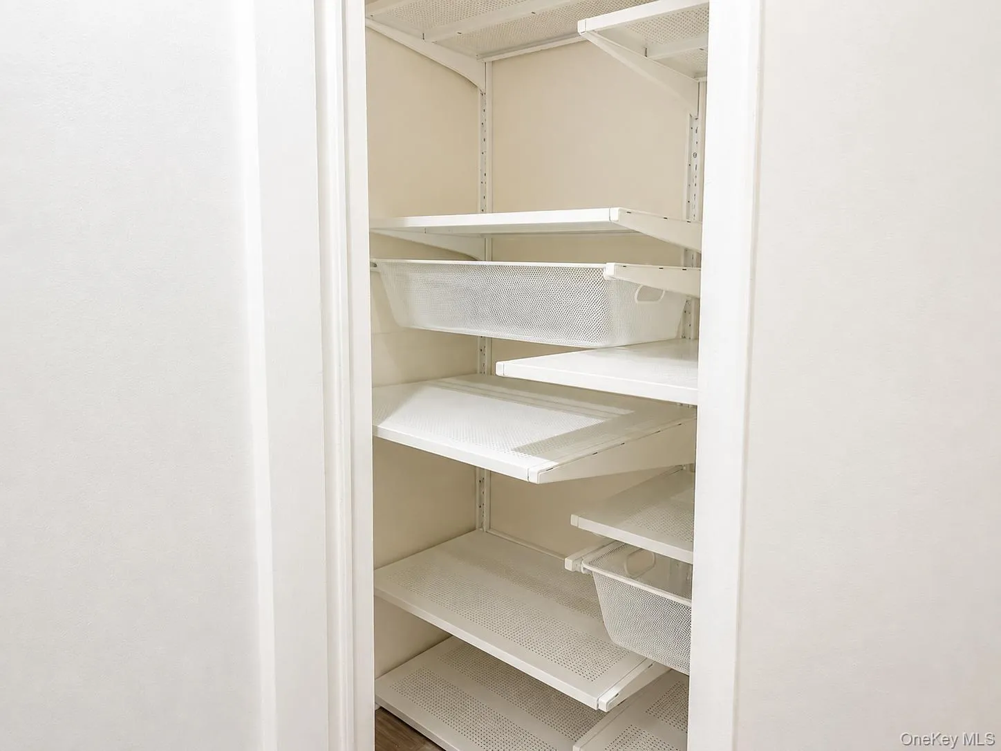 Built-in custom shelving system with multiple adjustable shelves and white wire baskets Built-in custom shelving system with multiple adjustable shelves and white wire baskets