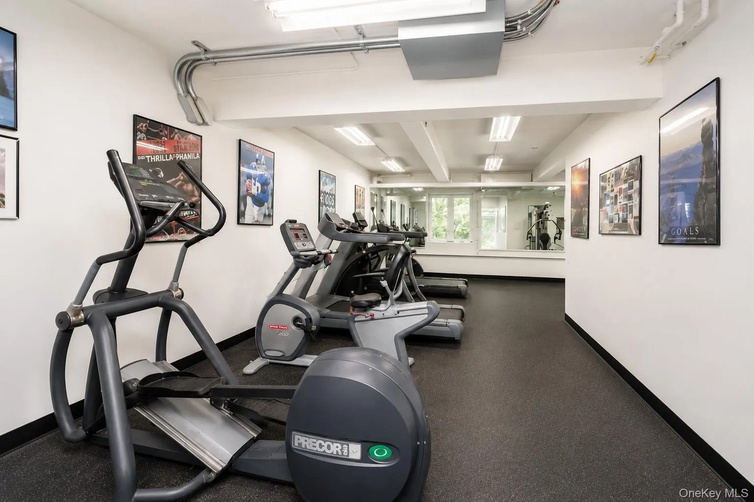 Fitness center with rubber flooring, extensive mirror wall, and multiple cardio machines Fitness center with rubber flooring, extensive mirror wall, and multiple cardio machines