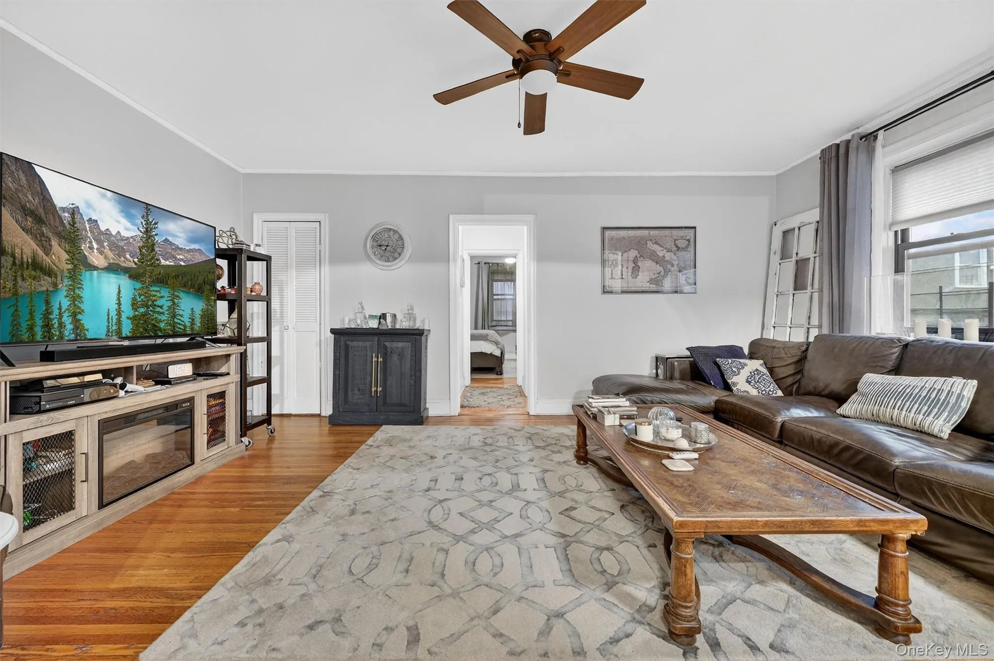 Living area with light wood finished floors, a ceiling fan, and ornamental molding Living area with light wood finished floors, a ceiling fan, and ornamental molding